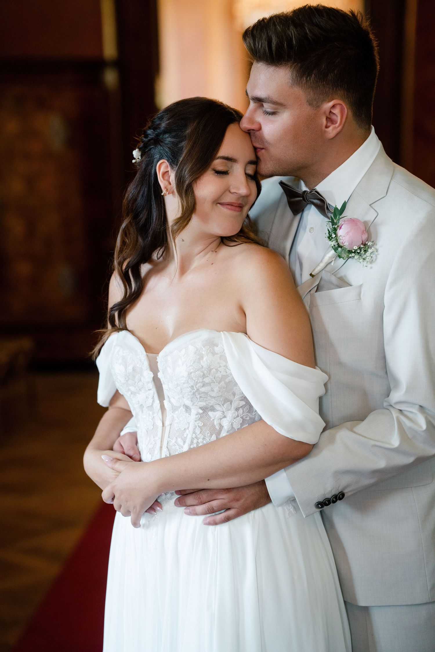 Romantic wedding dance poses in white attire against dark elegant backdrop.