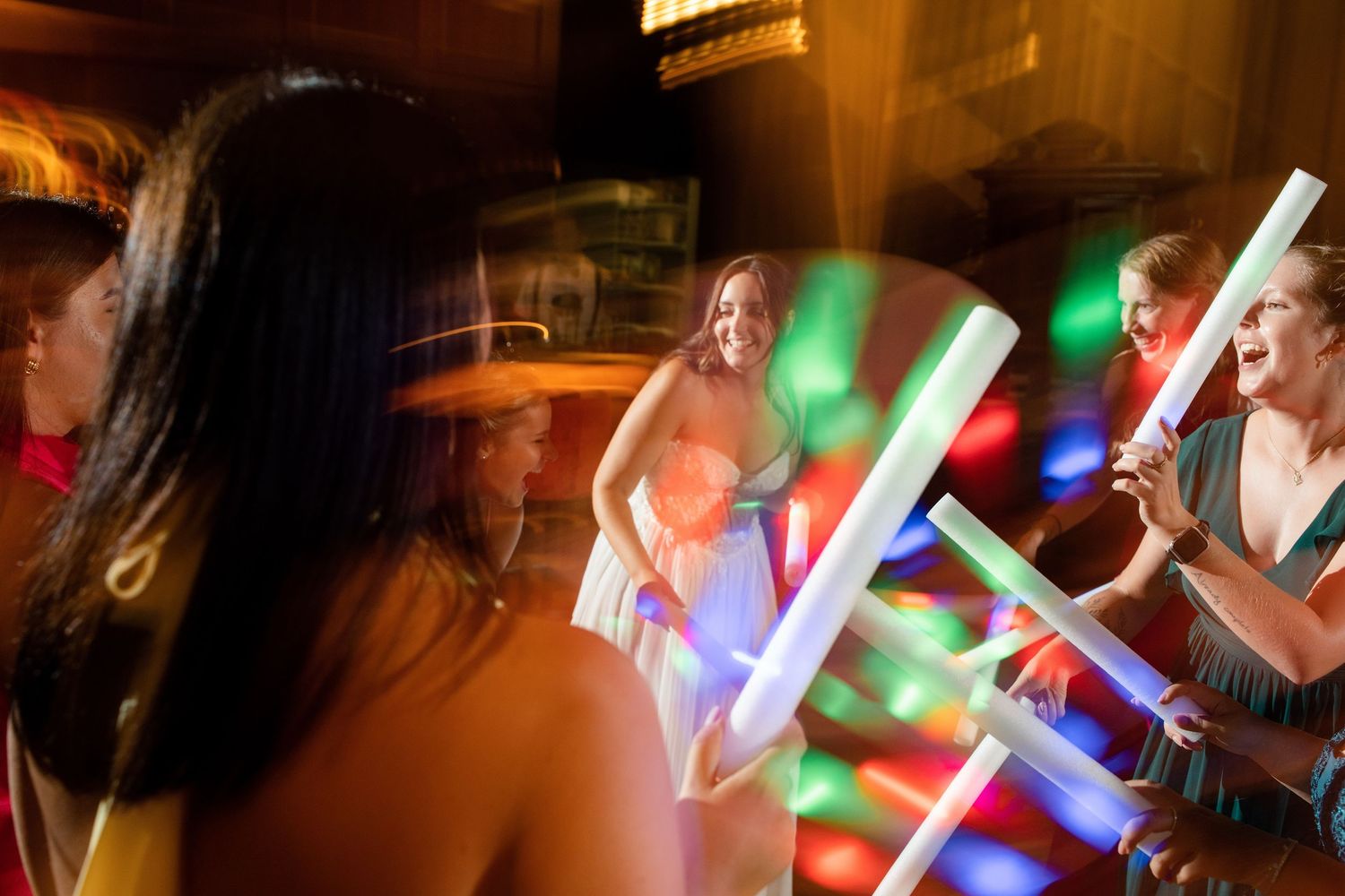 Guests dance with colorful LED light sticks creating a festive atmosphere at a reception.