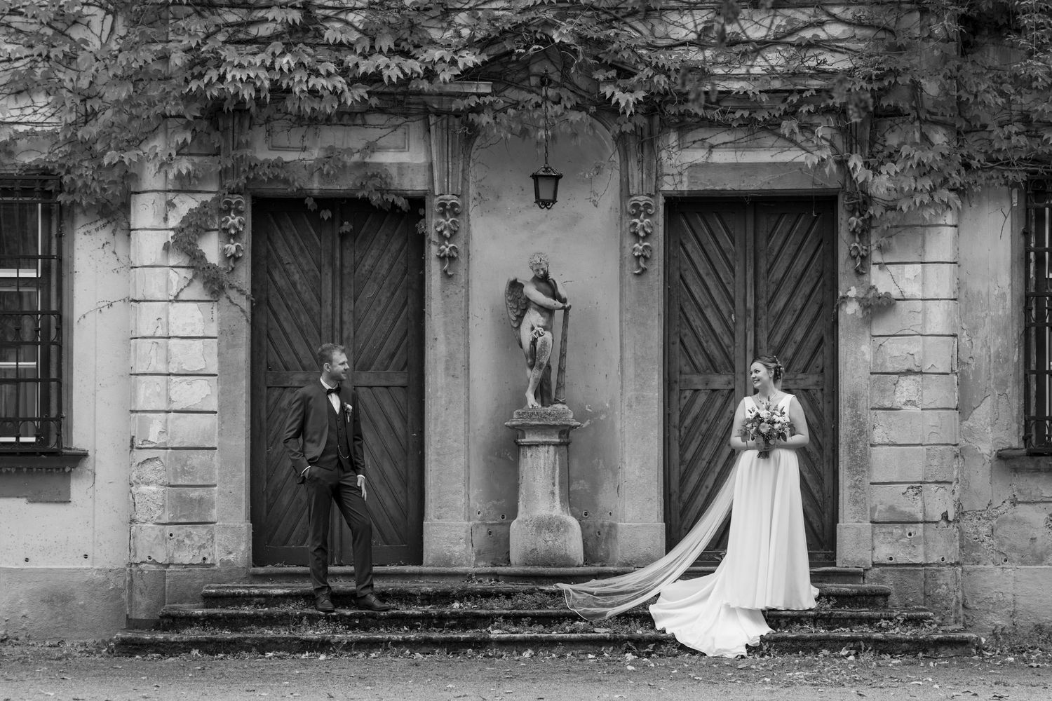 Black and white panoramic view of a historic building exterior with multiple doorways.