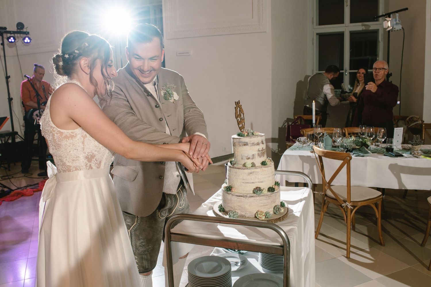 Wedding couple cuts their white tiered cake during the reception celebration.