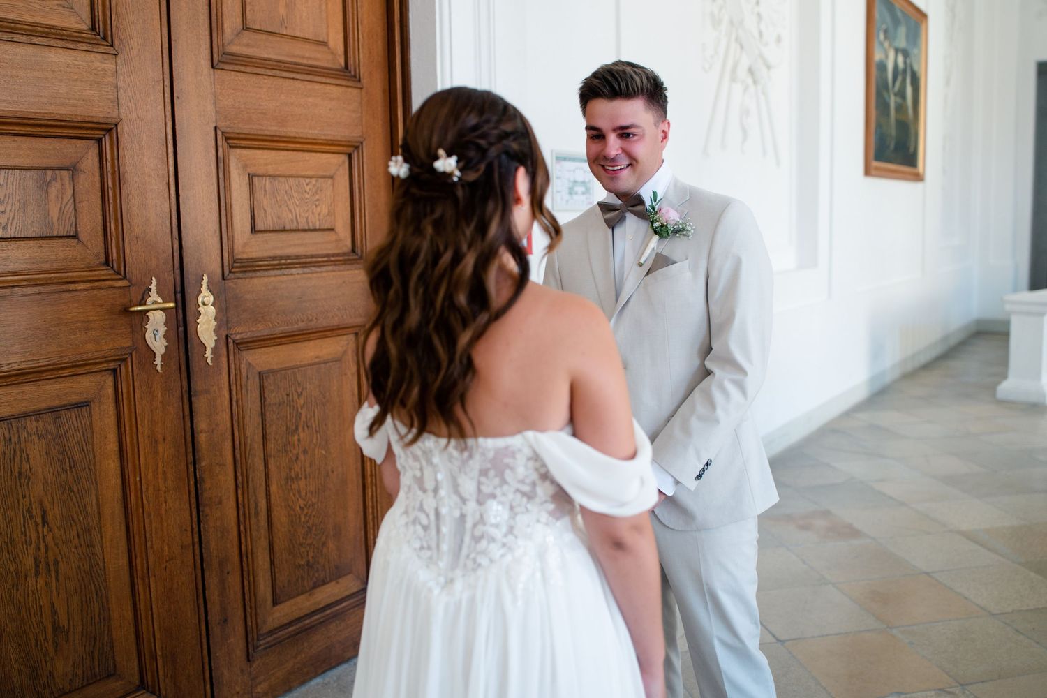 A romantic wedding couple shares a tender moment in front of ornate wooden doors.
