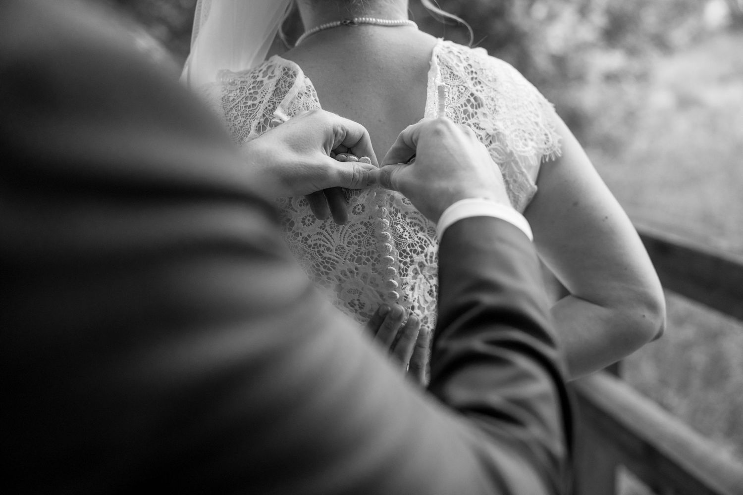 Black and white wedding photo showing a couple holding hands during an intimate outdoor ceremony.