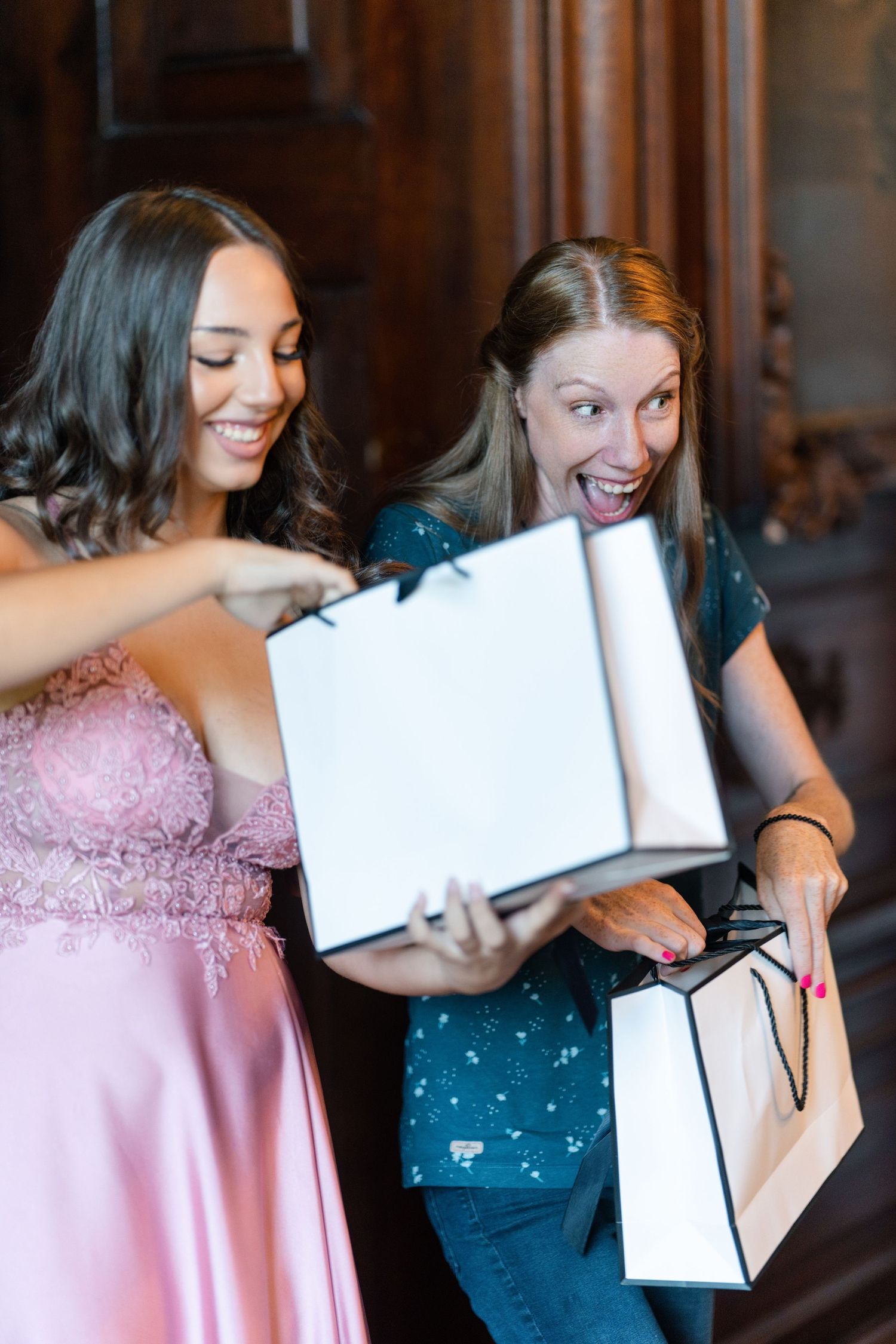 Two people excitedly looking at gift boxes and shopping bags during celebration.