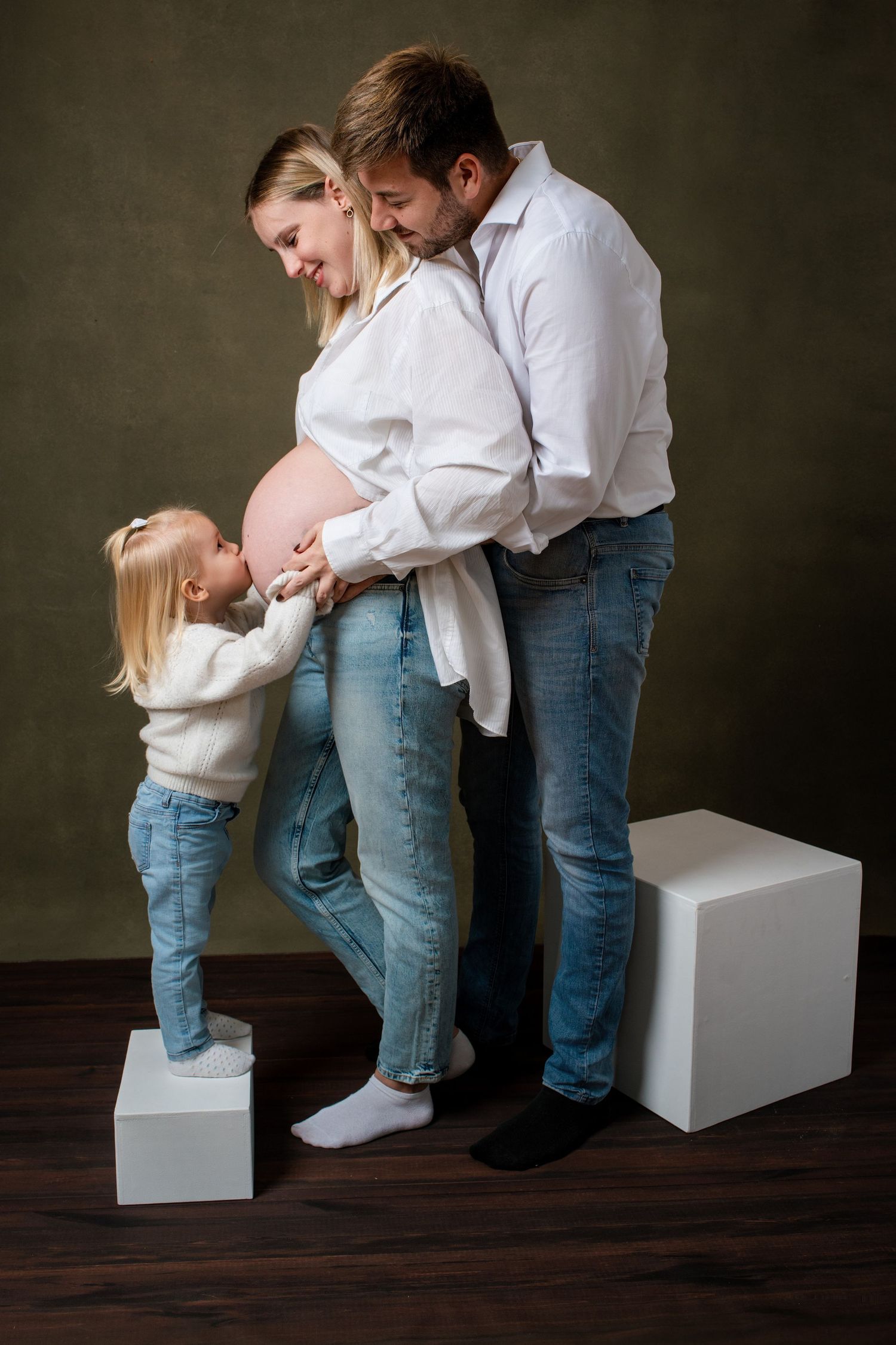 A sequence of four intimate family photos showing tender moments between parent and child on a white box against dark backdrop.