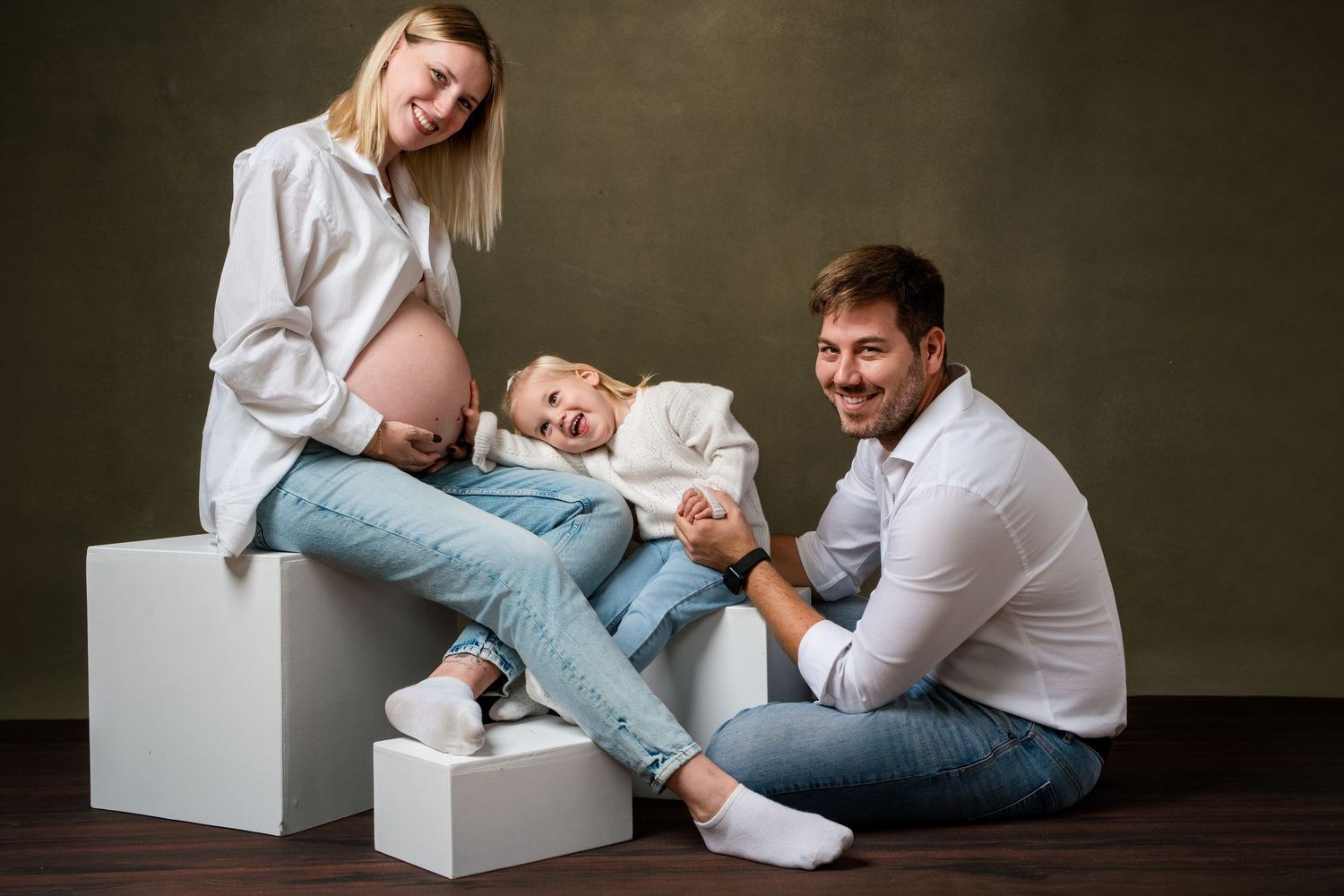 Professional studio photography session showing intimate family moments with a newborn baby against dark background.