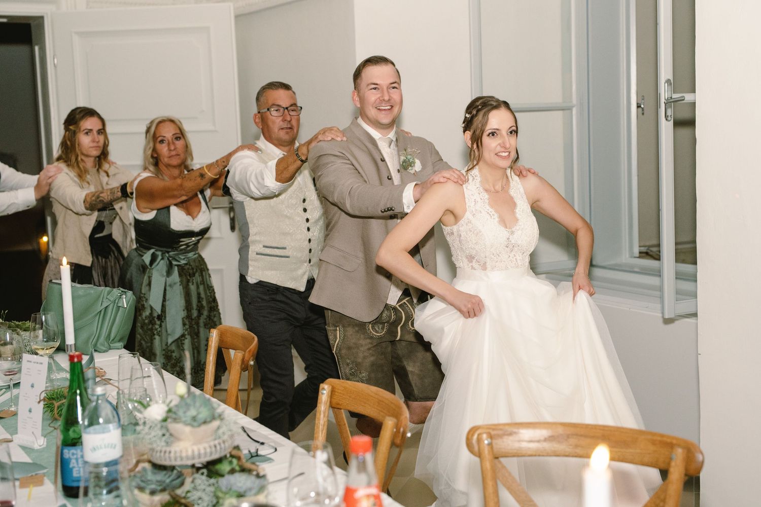Wedding reception party with guests celebrating and dancing in bright indoor venue.