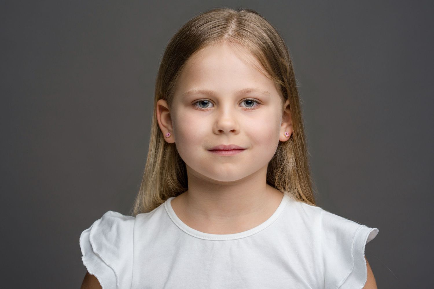 A series of similar headshots showing a young child in a white top against a dark background.