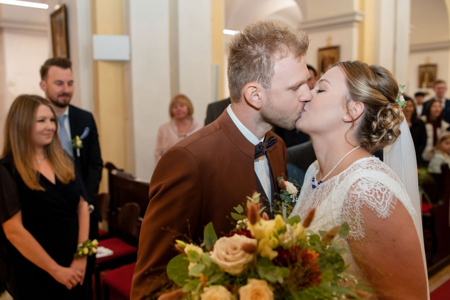 Wedding ceremony taking place in an elegant church interior with decorative floral arrangements.