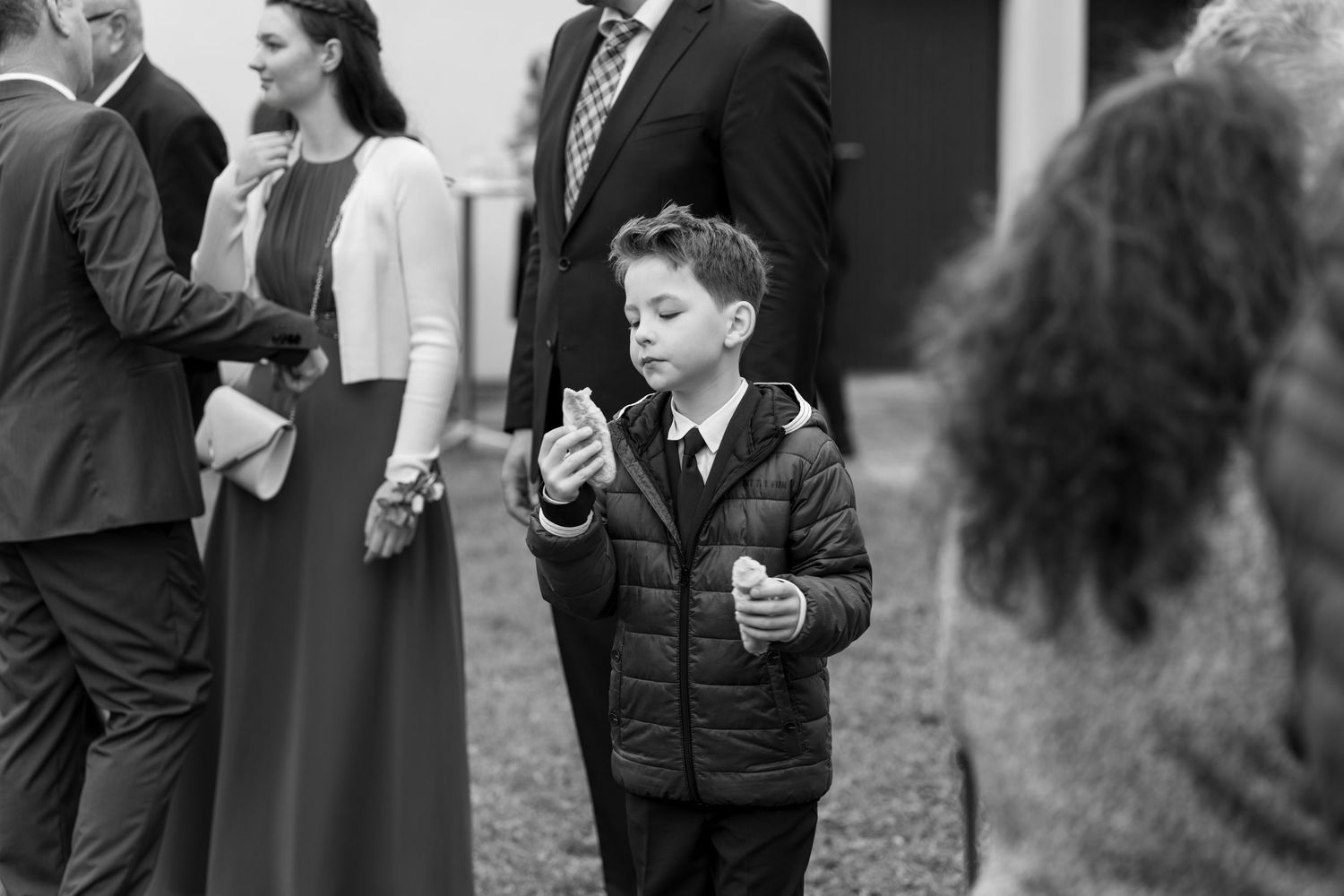 A young guest in a dark jacket enjoys refreshments during an outdoor event.