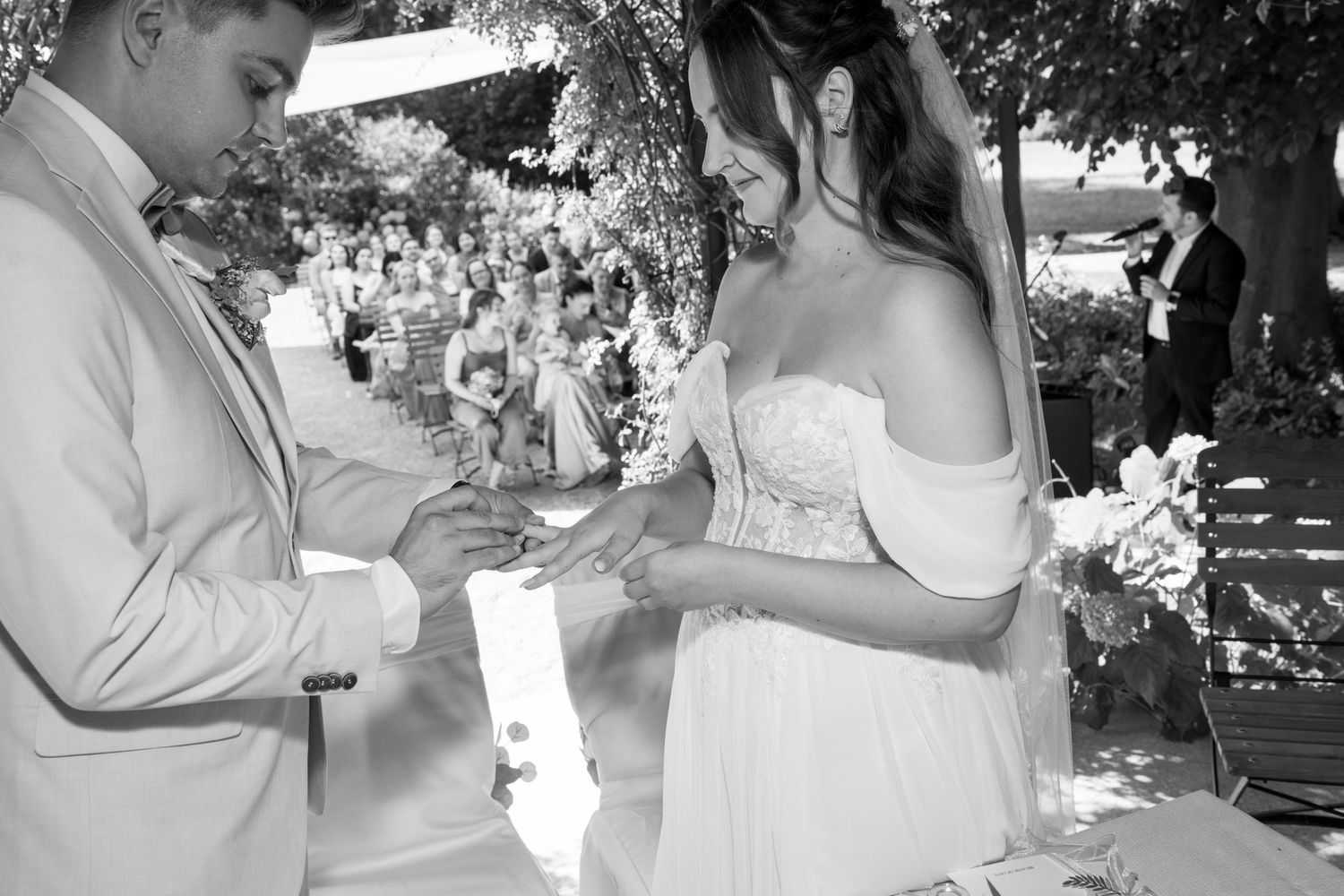 Black and white photo of a tender wedding ceremony moment in a garden setting.