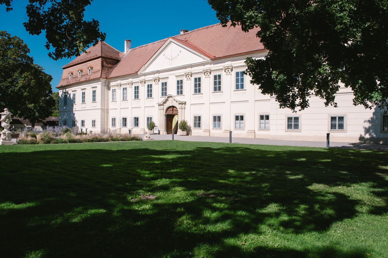 Panoramic view of a historic white mansion with manicured lawn on sunny day.