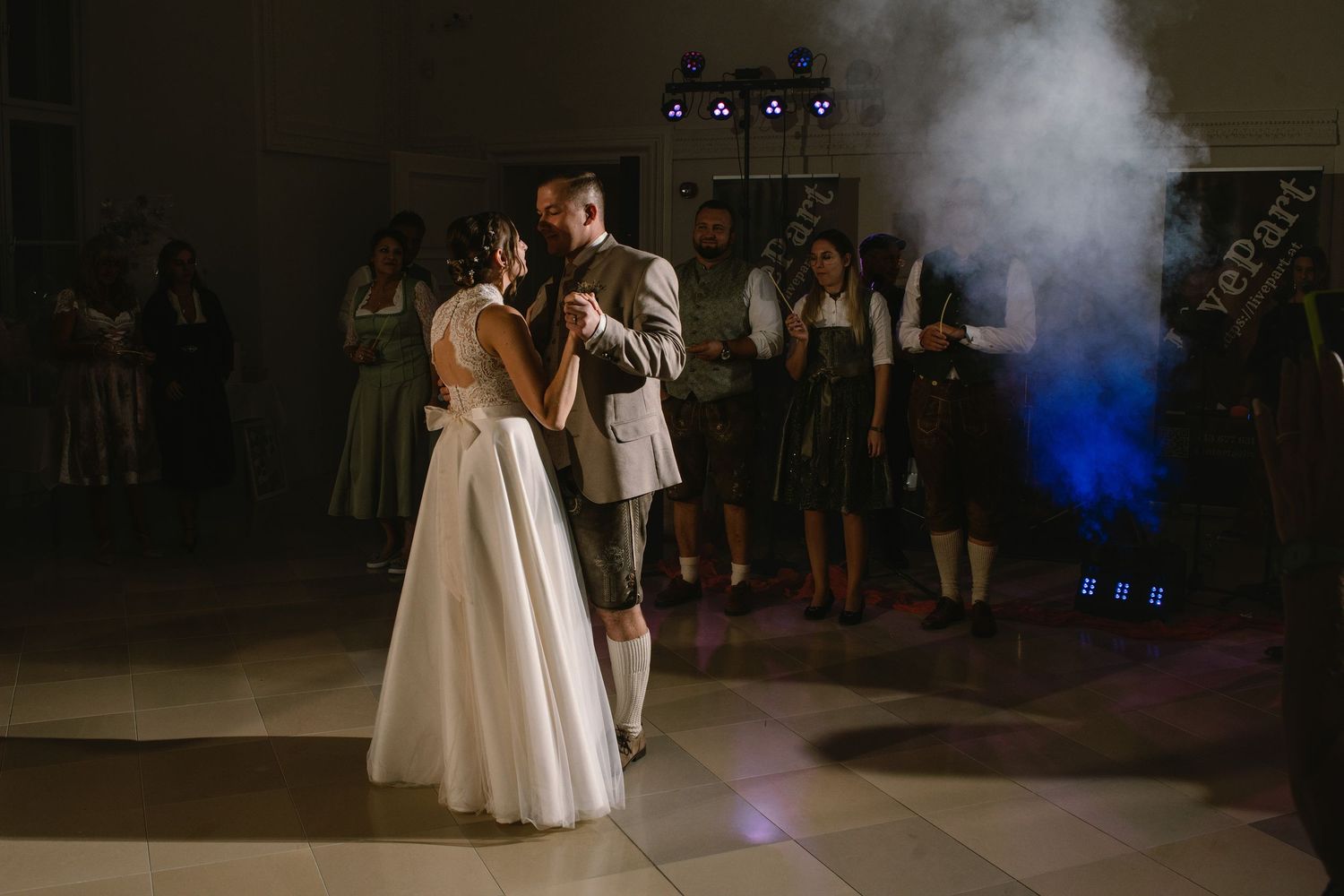 Atmospheric dance floor scene with fog and blue lighting at wedding reception.