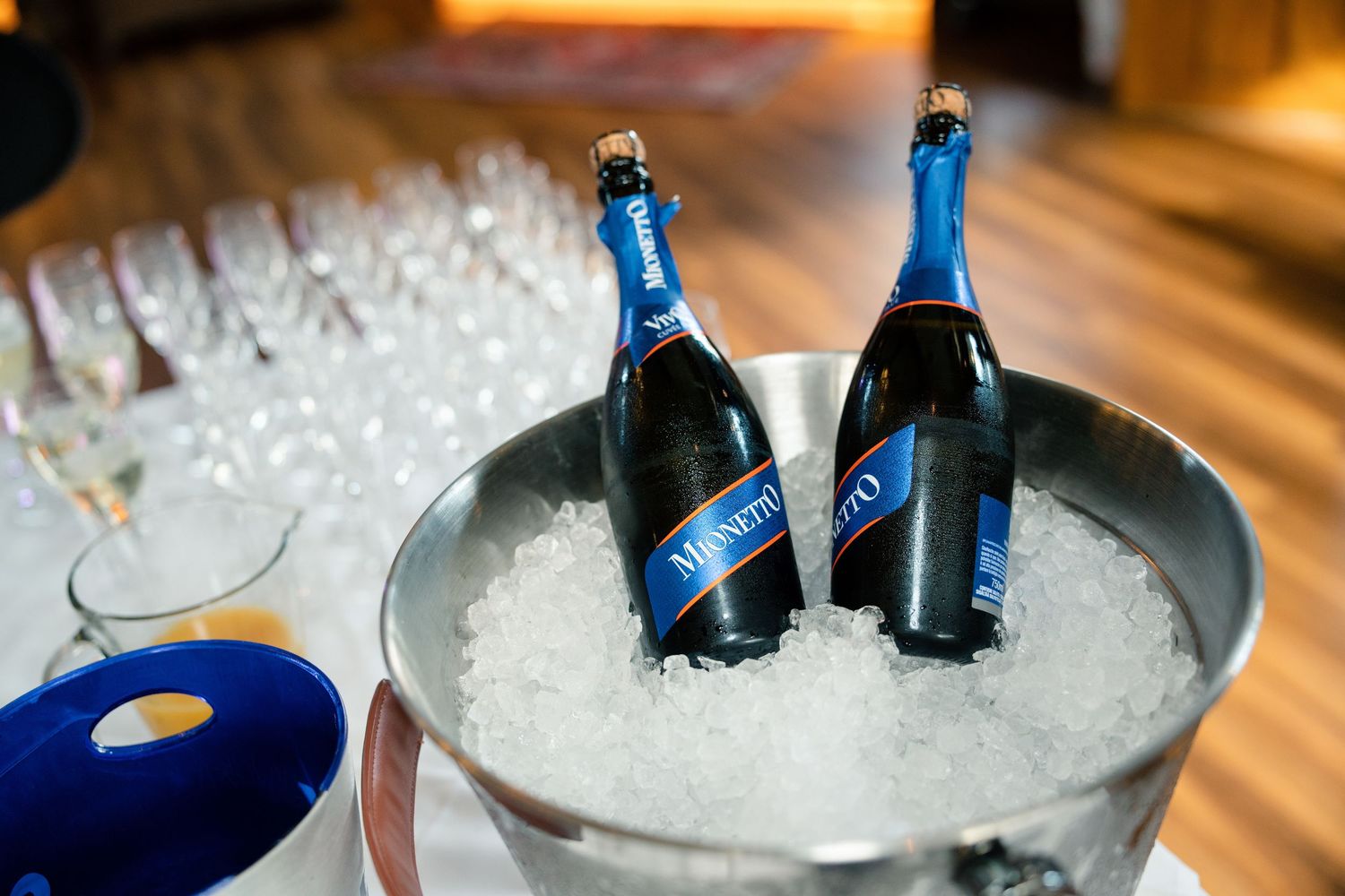 Blue champagne bottles chilling in ice bucket at wedding reception.