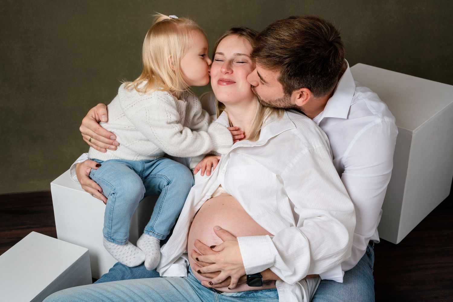 Intimate black and white maternity photo session showing tender moments between expectant parents at home.