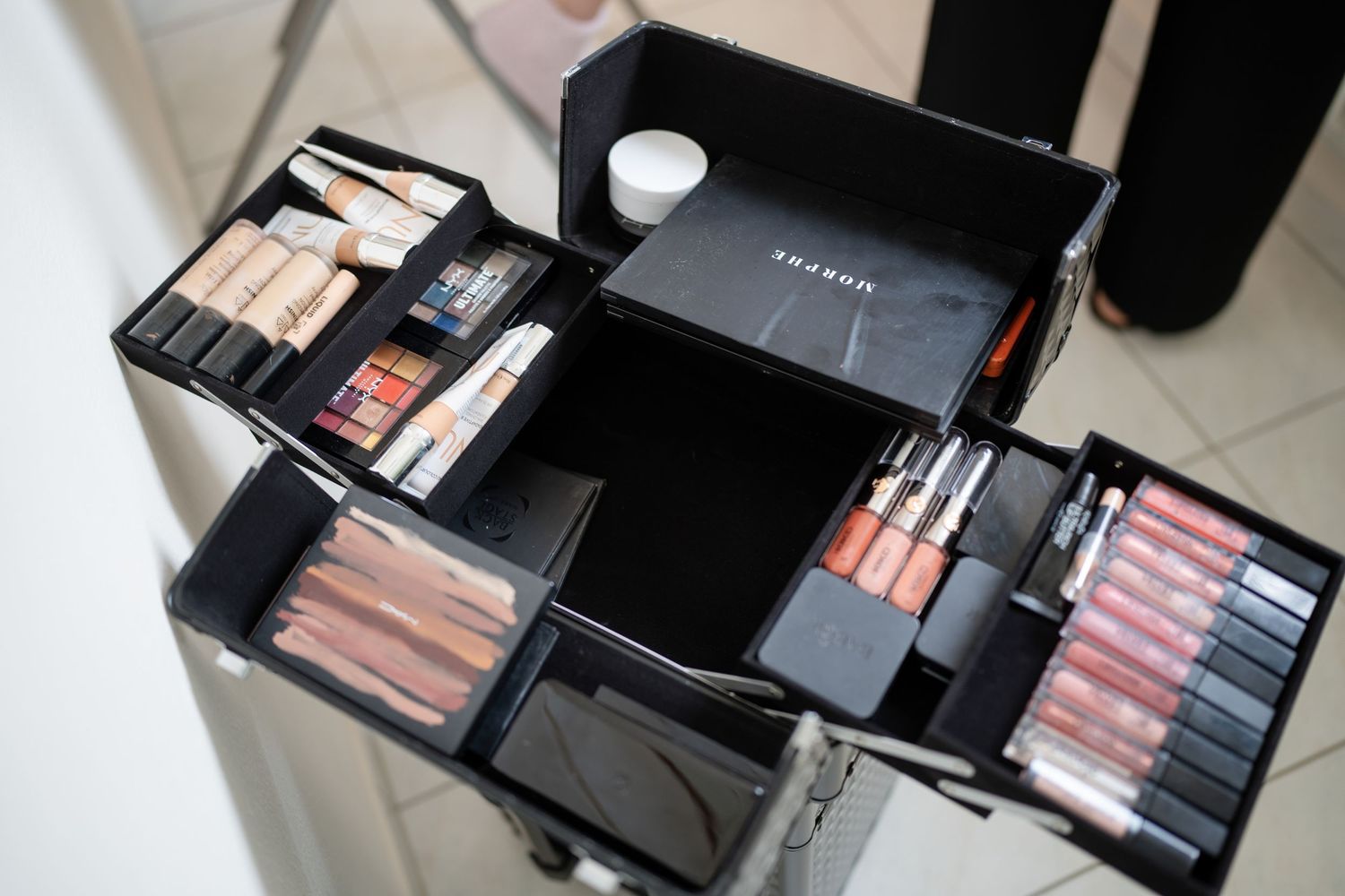 Makeup and cosmetics products neatly arranged in black cases and palettes.