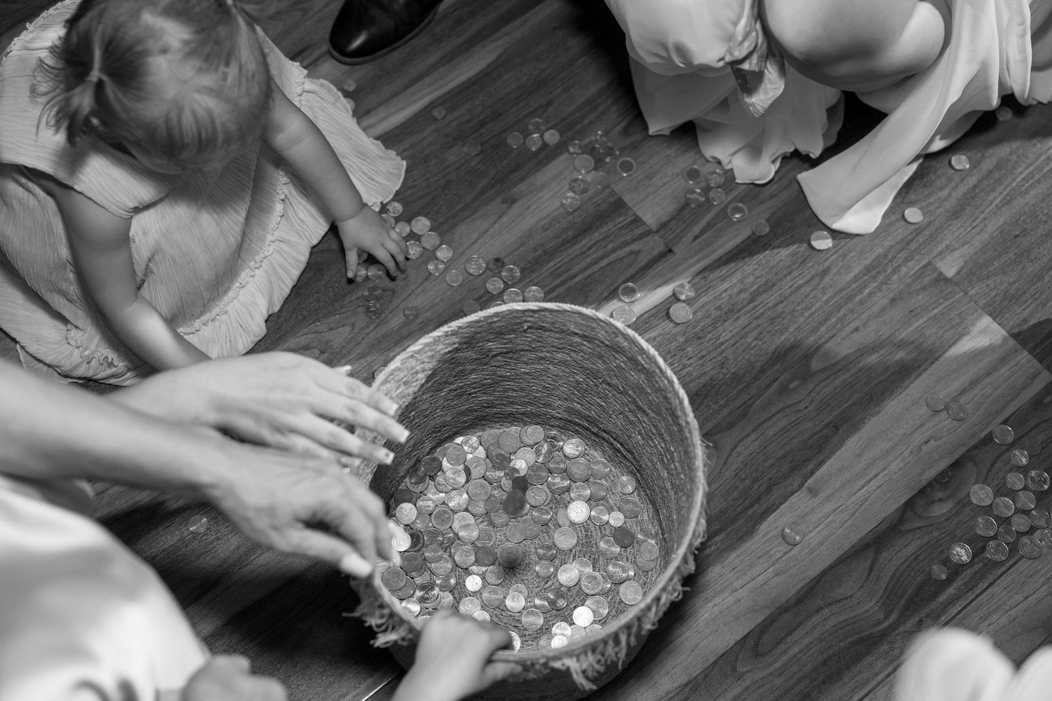 Close-up of hands collecting coins or small objects from a table surface.