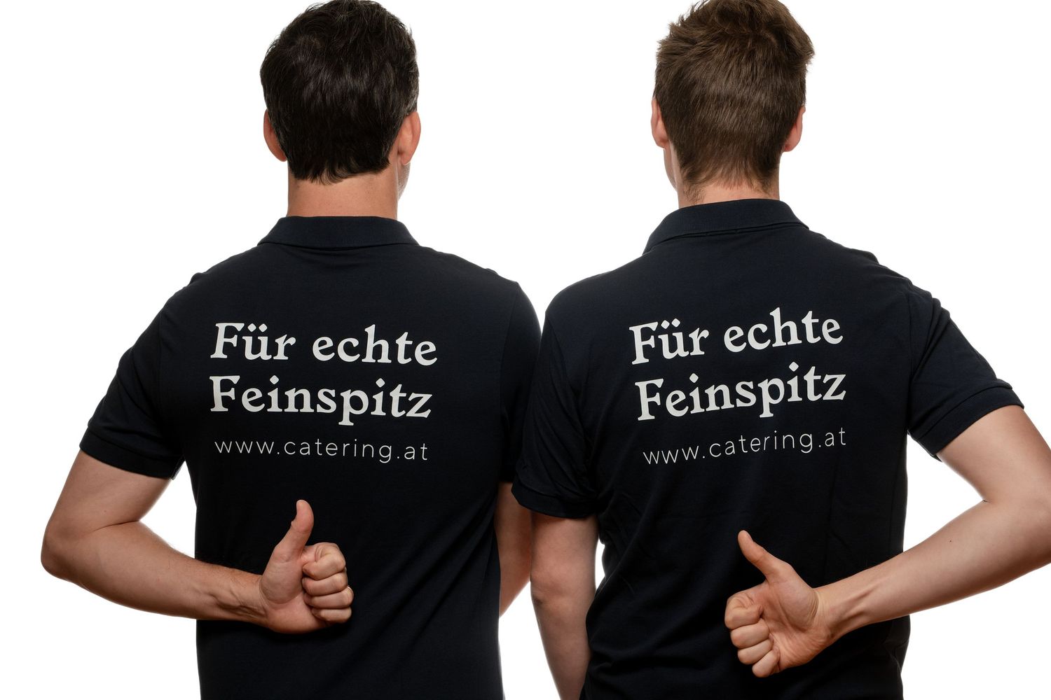 Two men in black polo shirts showing catering company logo text Fur echte Feinspitz and www.catering.at, giving thumbs up.