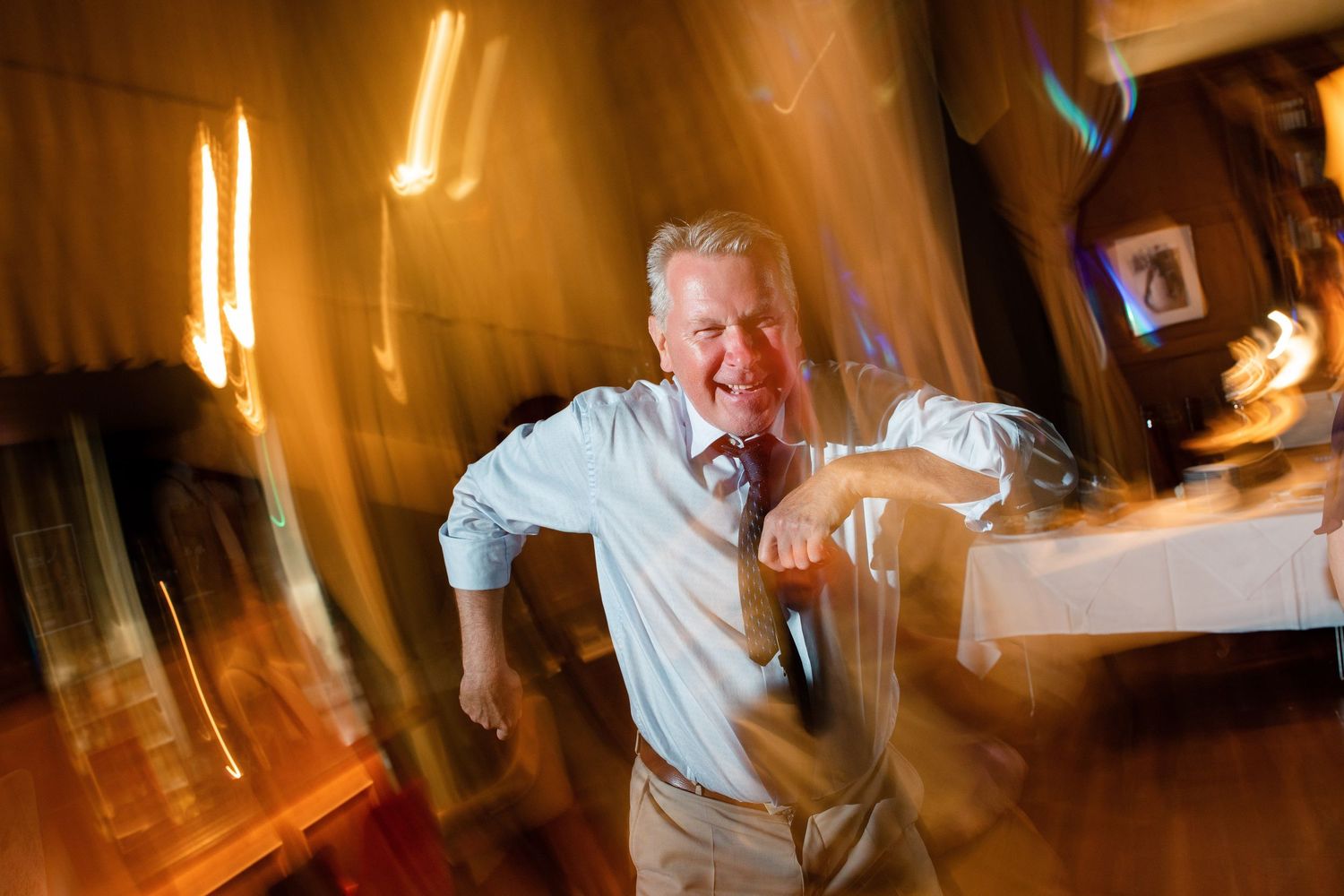 A guest dances energetically at a wedding reception with motion blur effects.