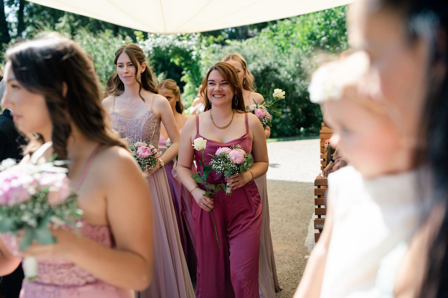 Wedding party poses outdoors with bridesmaids in burgundy dresses.