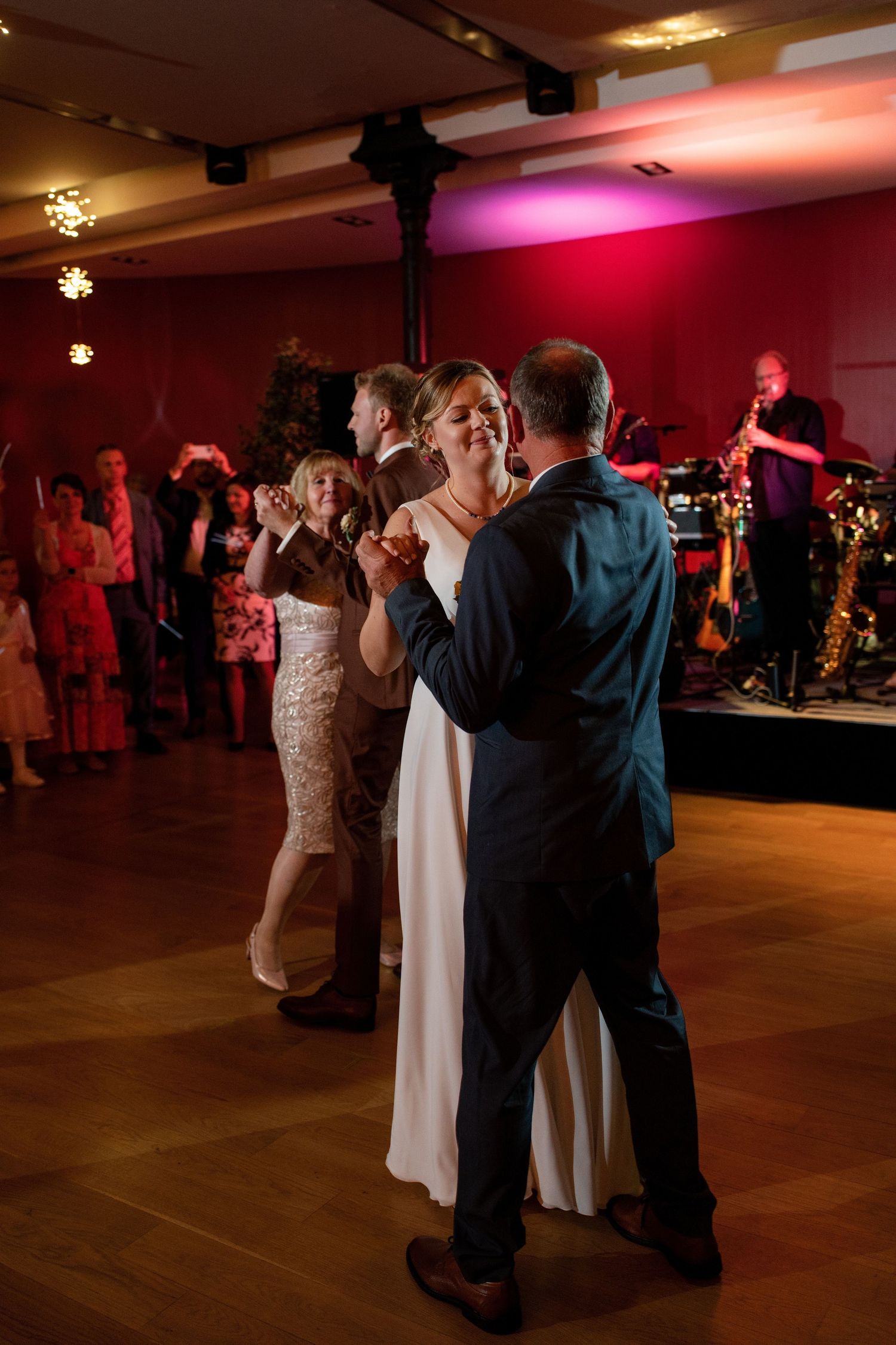Wedding guests dancing together in a reception hall with warm lighting and festive atmosphere.