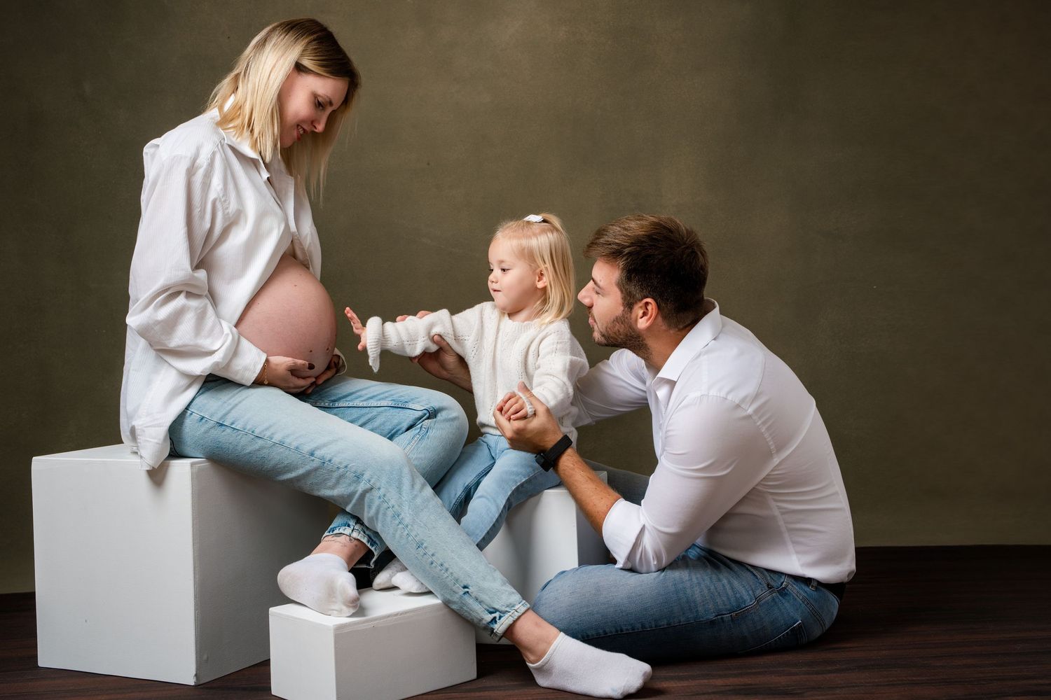 A series of candid family photos showing tender moments between parents and baby in a minimalist studio setting.