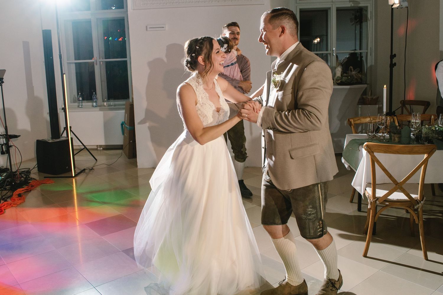 Romantic wedding dance captured in warm lighting with guests watching from the sides.