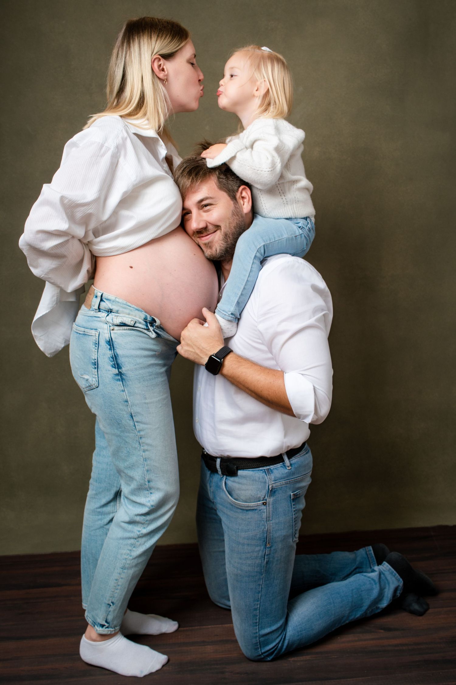 Sweet family maternity session with toddler and parents in matching white shirts and jeans.
