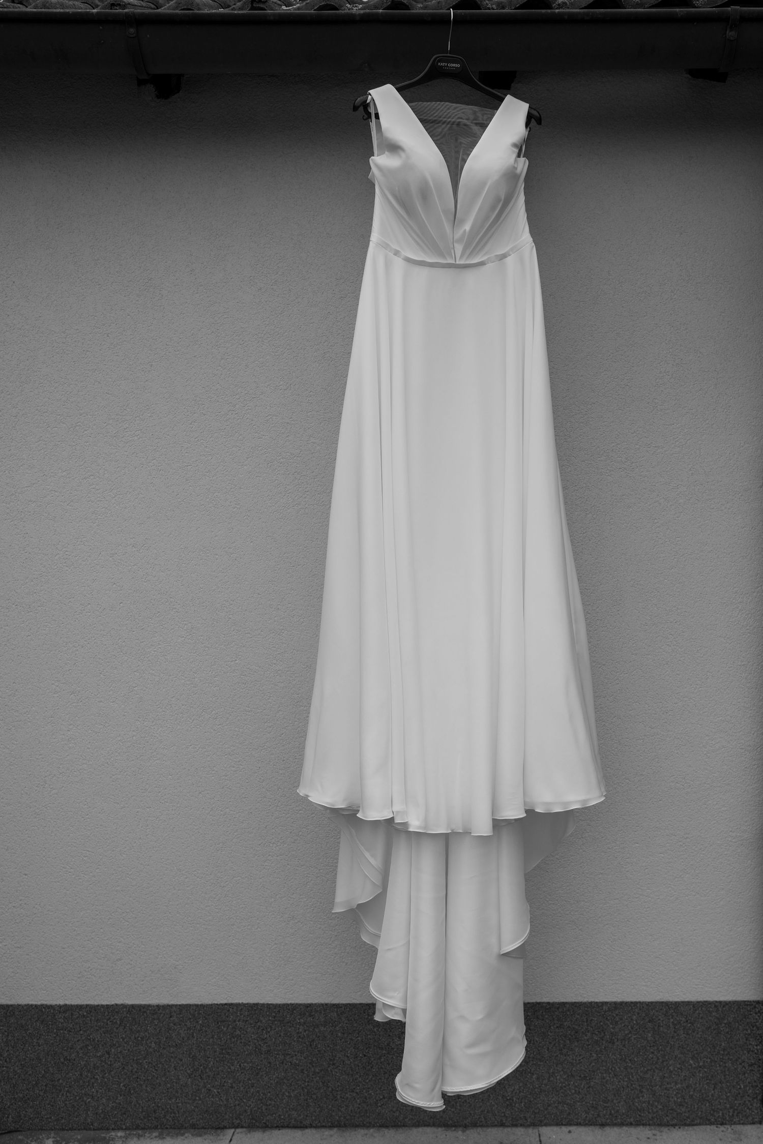 A collection of elegant white wedding dresses displayed against a grey wall.