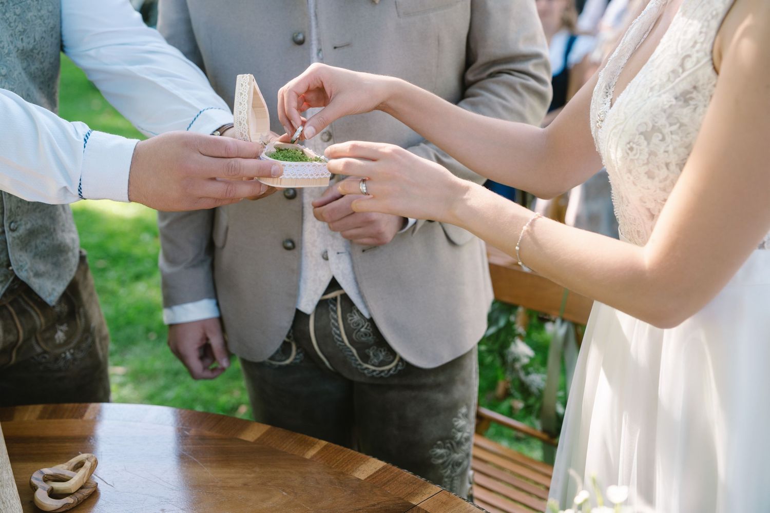 Wedding ceremony guests exchanging rings during an intimate outdoor celebration.