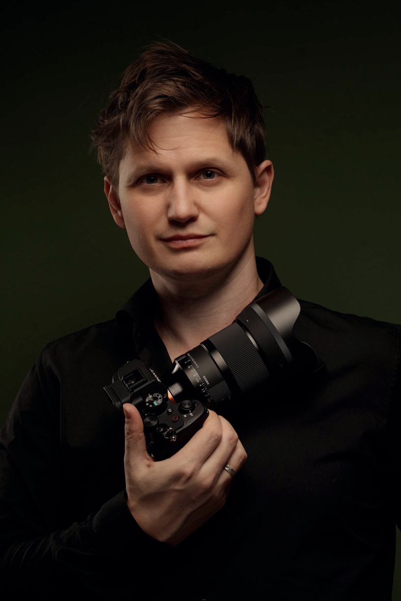 A series of moody studio portraits in dark lighting showing someone holding a camera against a black background.