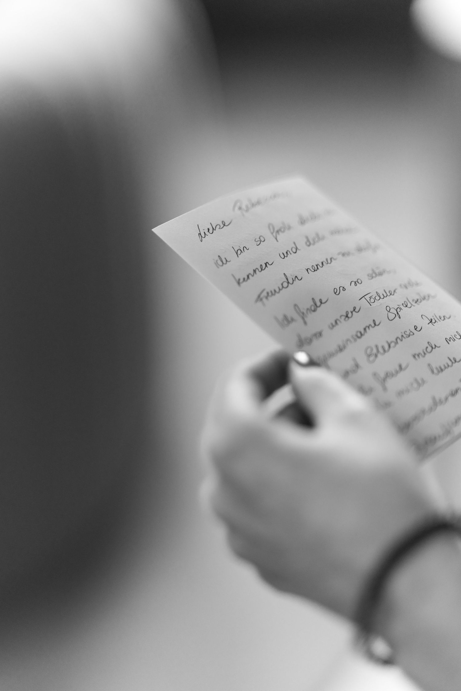 Close-up black and white photo of hands holding handwritten note or letter.