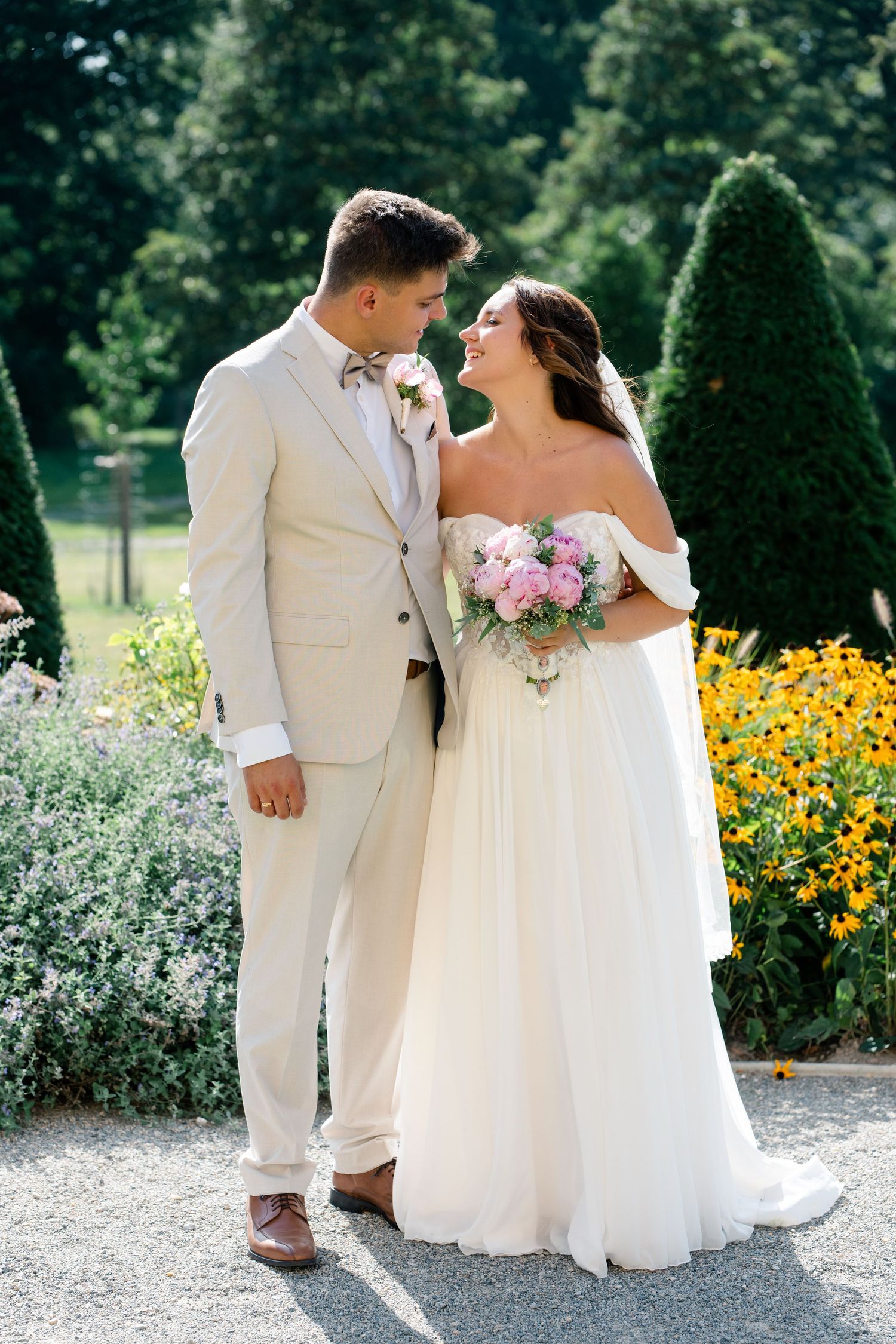 A couple shares intimate moments in a garden with yellow flowers and greenery.