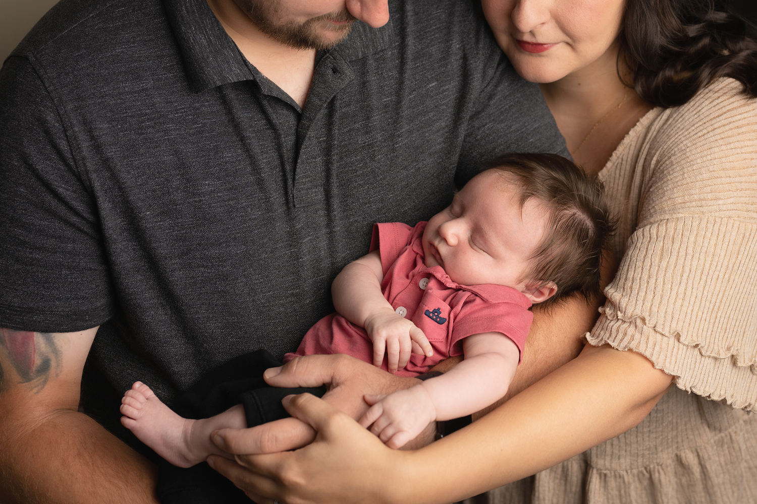 Parents holding and looking lovingly at their newborn baby in casual home setting.