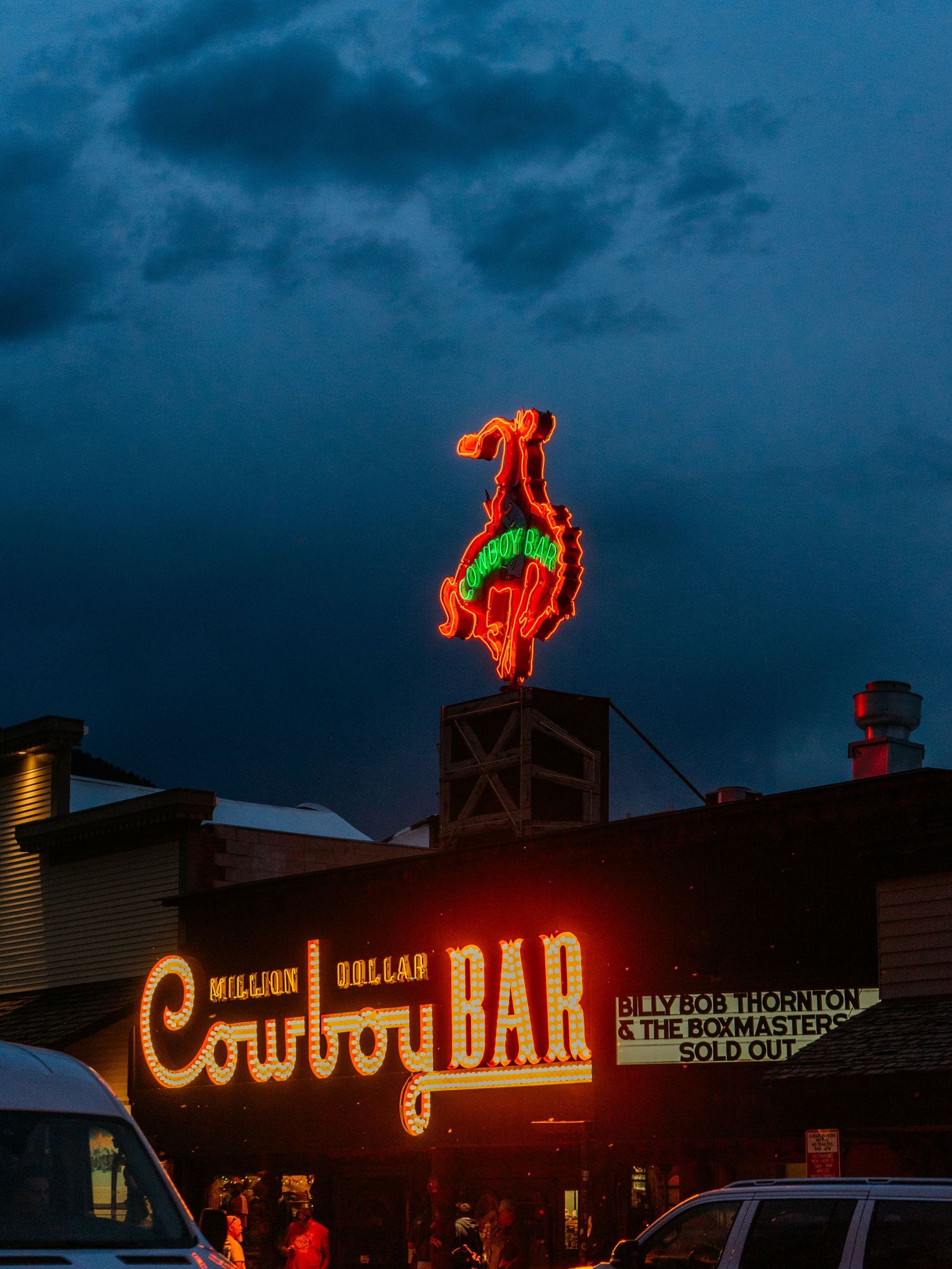 Neon sign of the Million Dollar Cowboy Bar glows at dusk in Jackson Hole, Wyoming, with a bucking bronco on top.