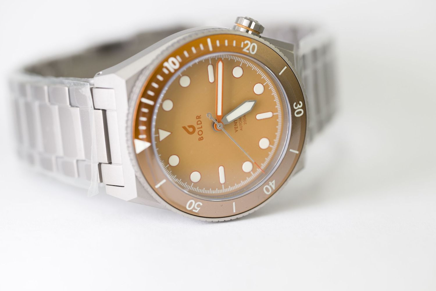 Close-up of a diver's watch with bronze dial and bezel on a stainless steel bracelet.