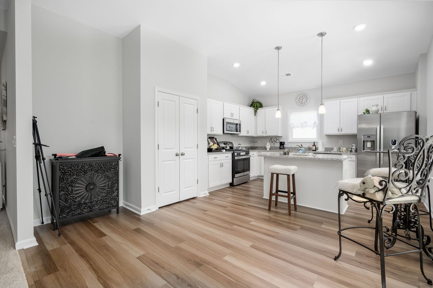 Modern kitchen with white cabinets, stainless steel appliances, island seating, and hardwood floors.