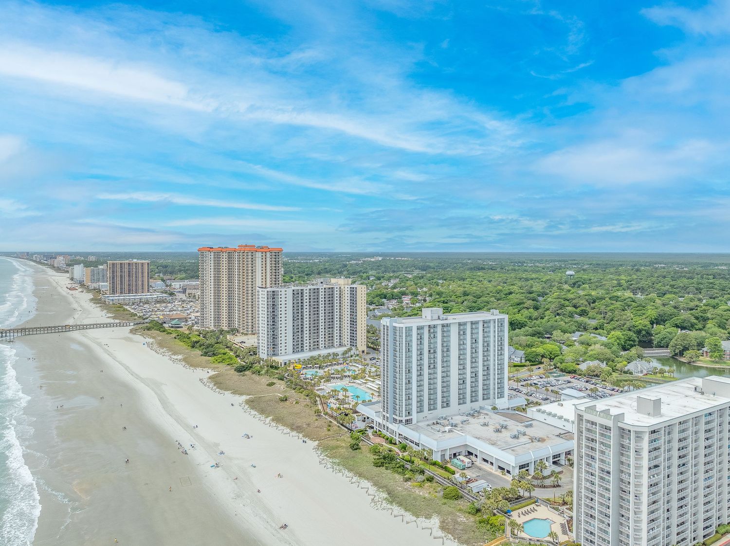 Aerial view of Myrtle Beach coastline with high-rise hotels and blue ocean under partly cloudy sky.