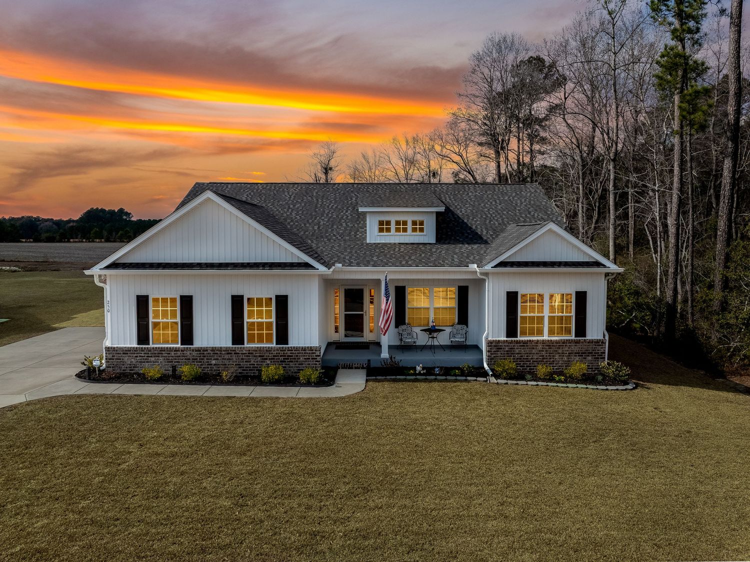 White craftsman-style home with covered porch and black shutters at golden sunset.