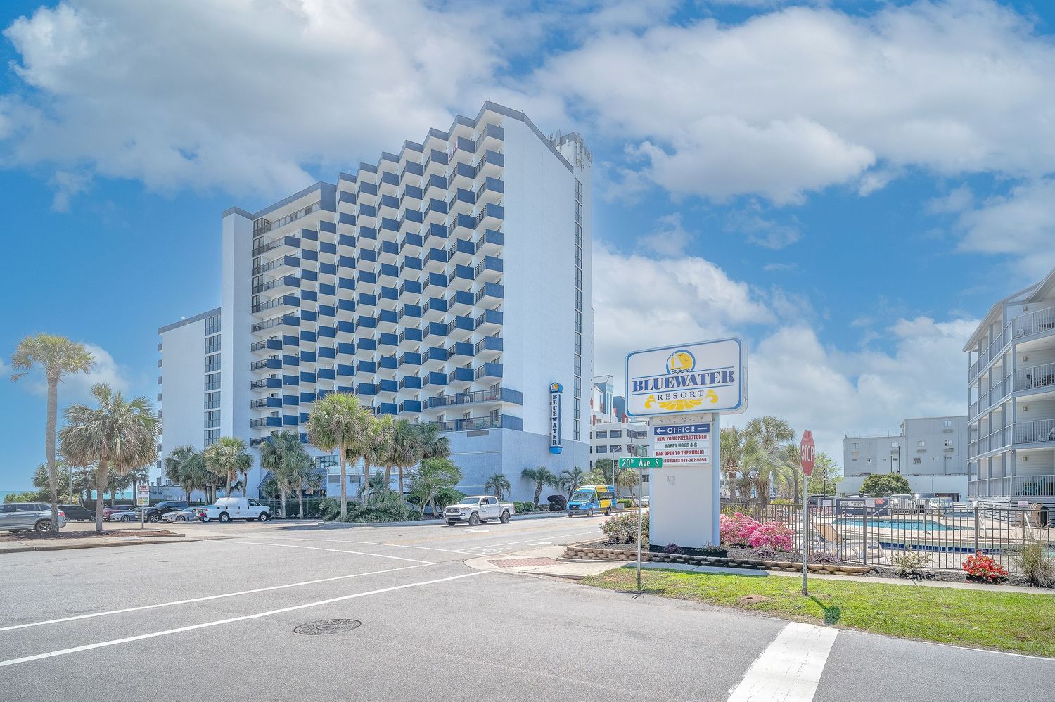 Bluewater Resort high-rise building exterior with palm trees and parking lot in Myrtle Beach.