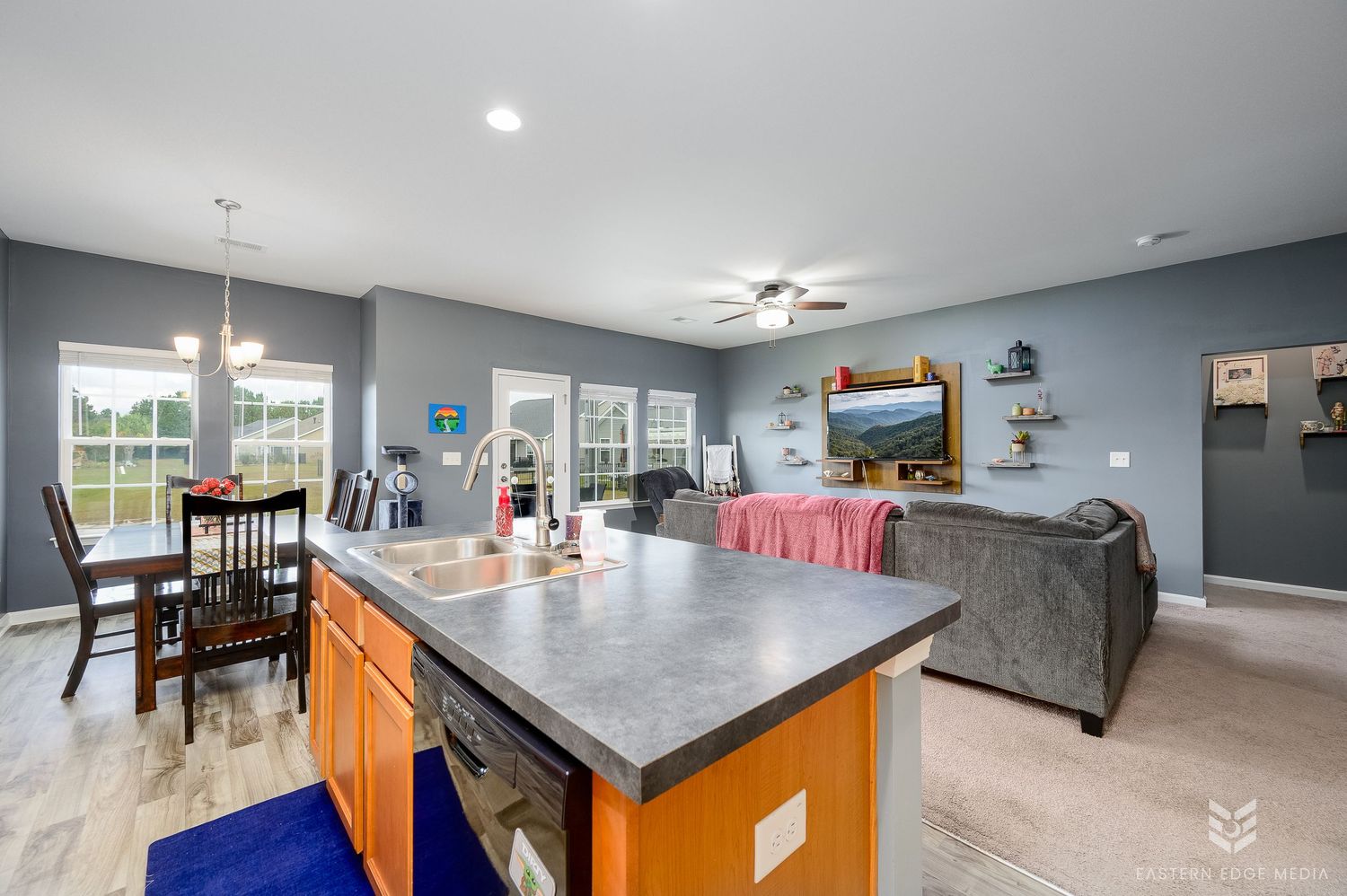 Open-concept kitchen with dark granite island, carpet flooring, and connected living and dining areas.
