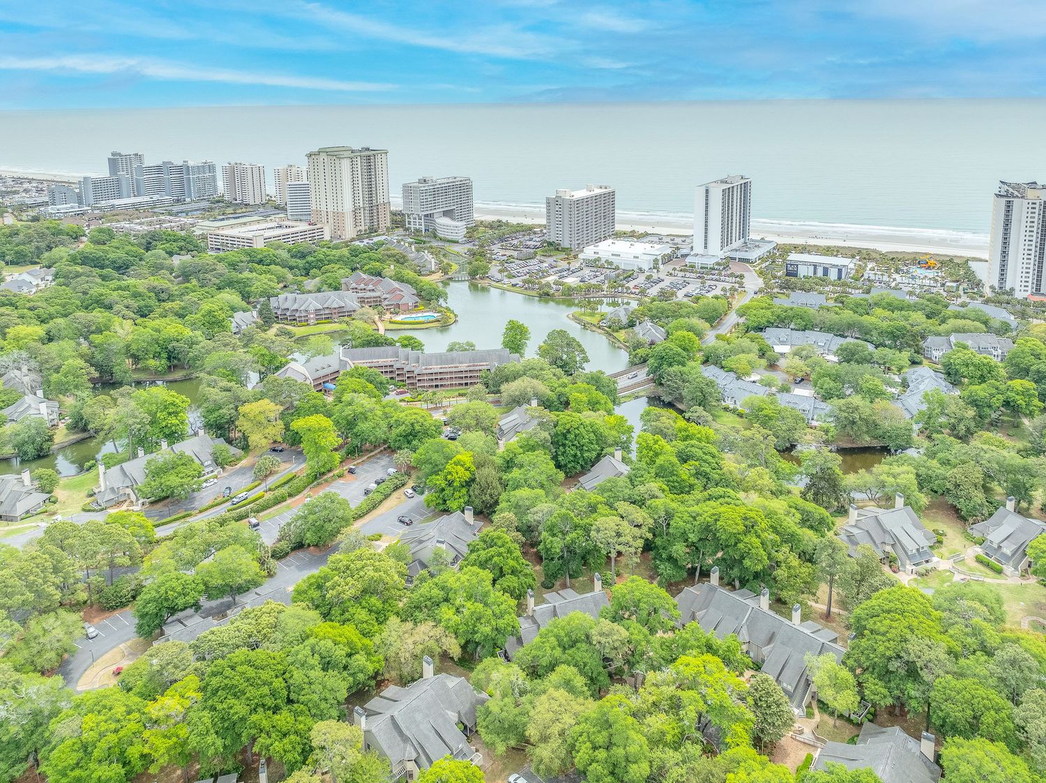 Aerial view of lush green coastal community with lakes and ocean visible in background.