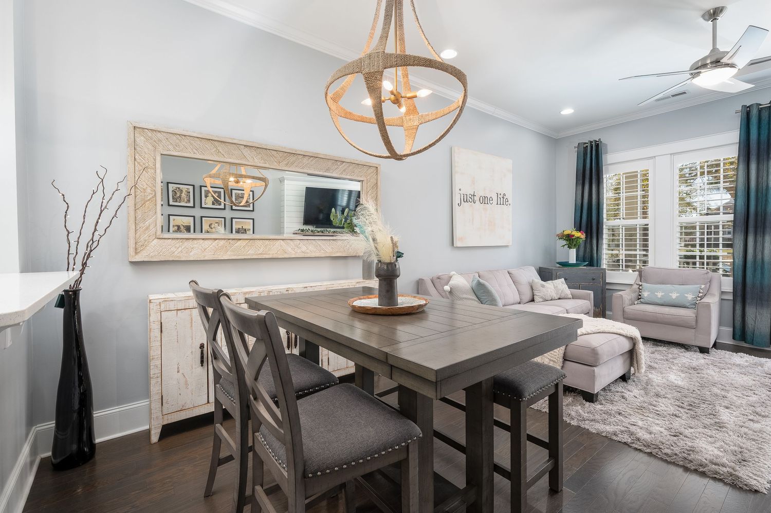 Elegant dining room with dark wood table, chandelier, ceiling fan, and plantation shutters.