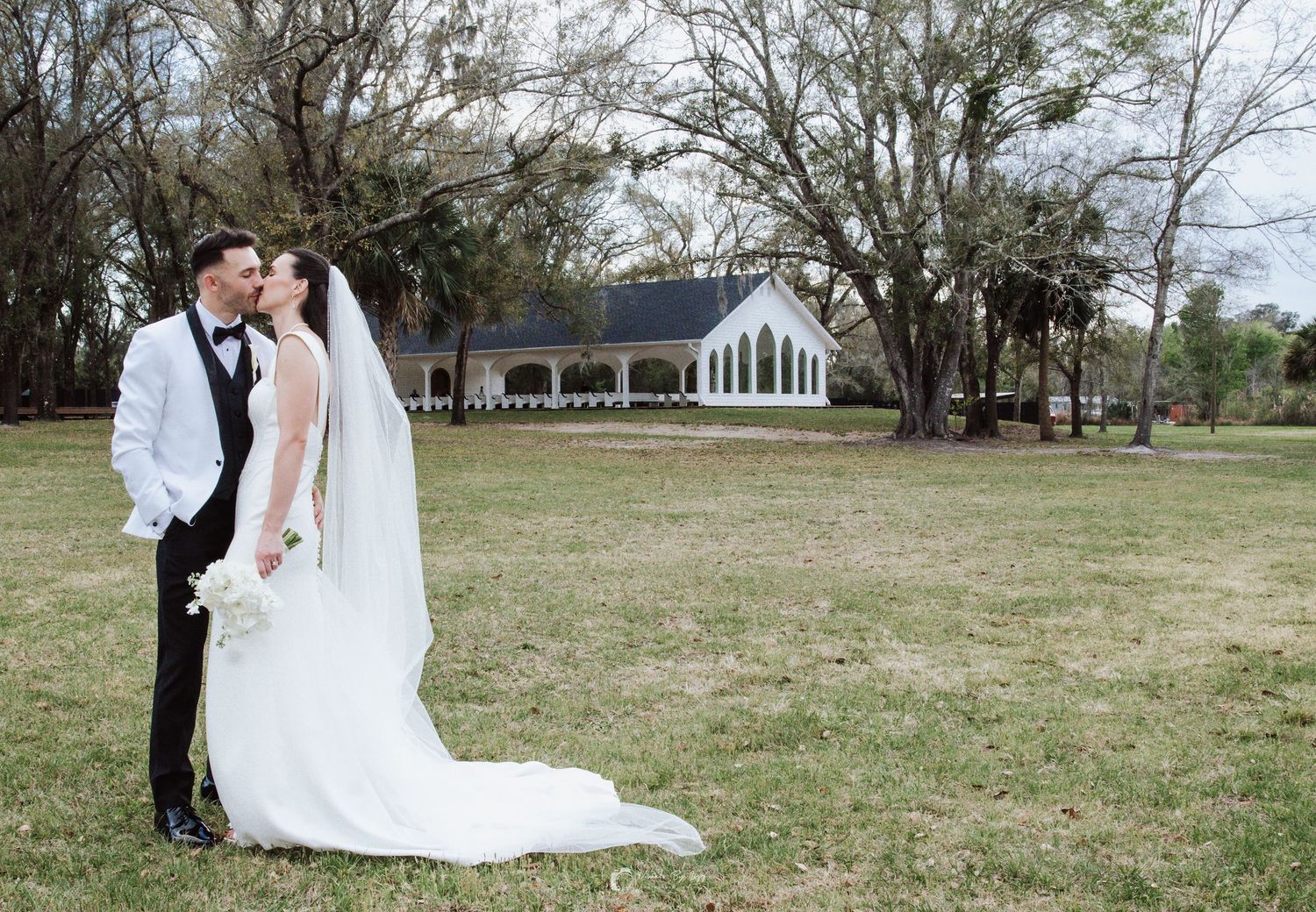 Bride and groom kissing in front of Whitewood Ranch chapel, De Leon Springs FL — Visuals by Lizz, Treasure Coast wedding photographer