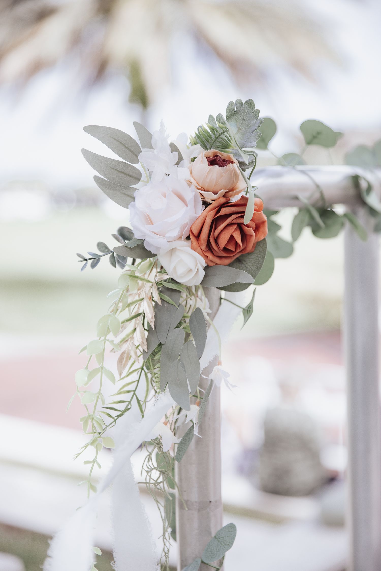 Romantic floral arrangement with pink and mauve roses, eucalyptus leaves, and trailing greenery.