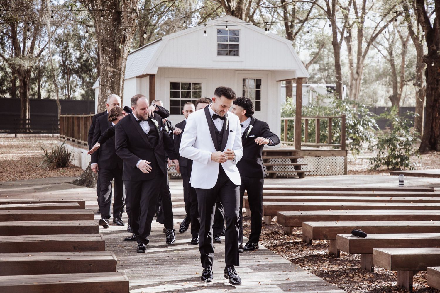 A group in formal attire walks together along an outdoor path in a natural setting during a special occasion.
