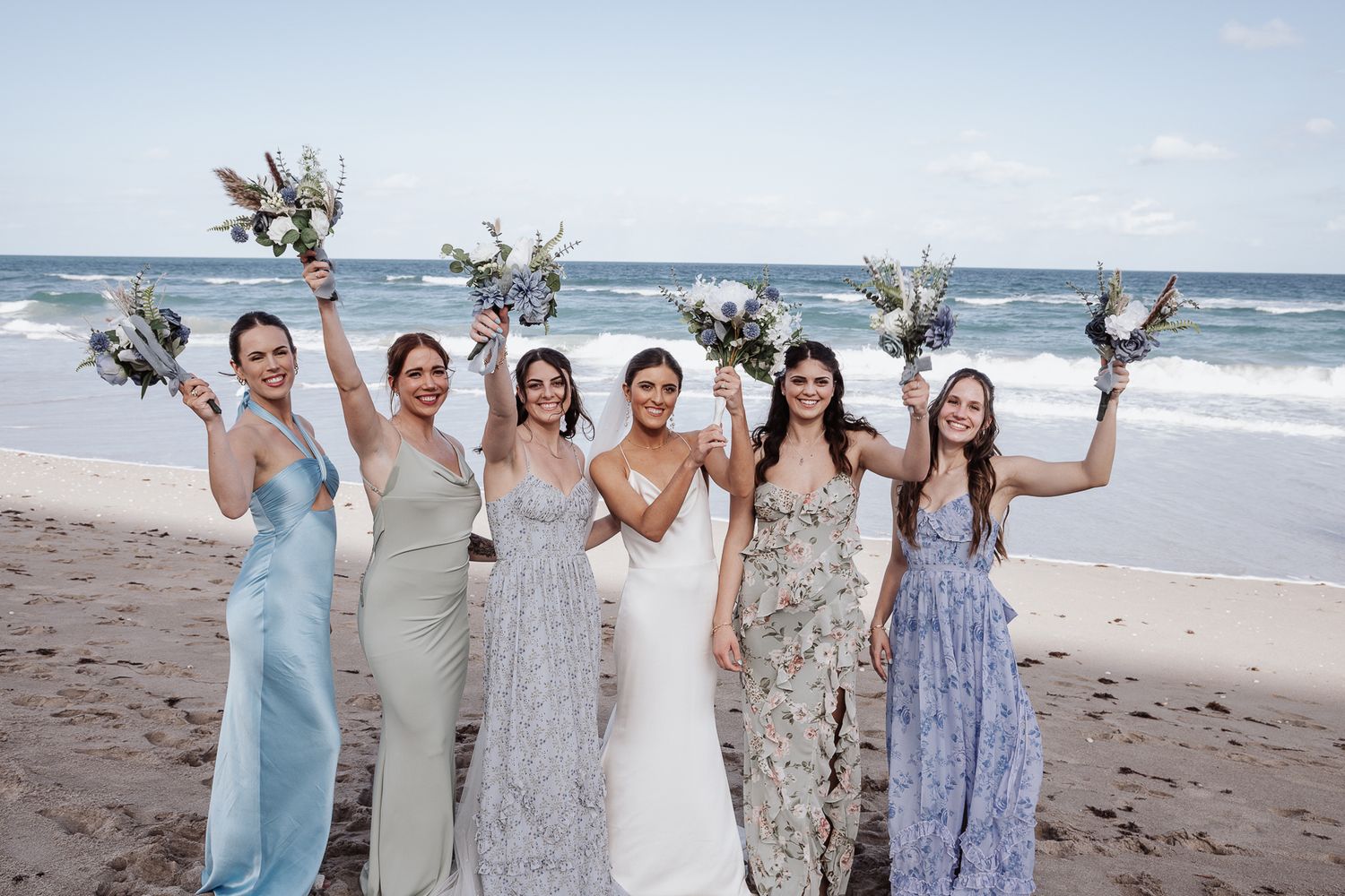 A group celebrates joyfully together on a sunny beach with ocean waves in the background. Jupiter, Florida
