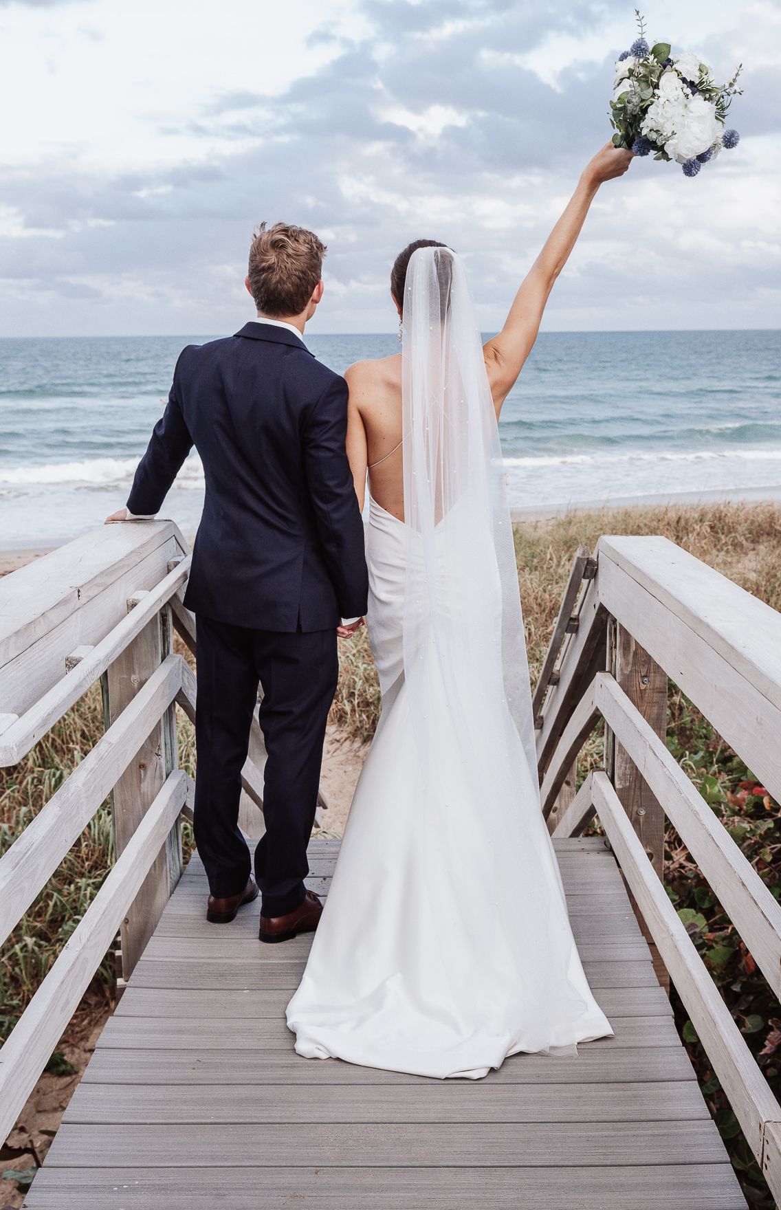 Bride and groom celebrating on boardwalk at Oceanfront at Windmill Events, Jensen Beach FL — Visuals by Lizz