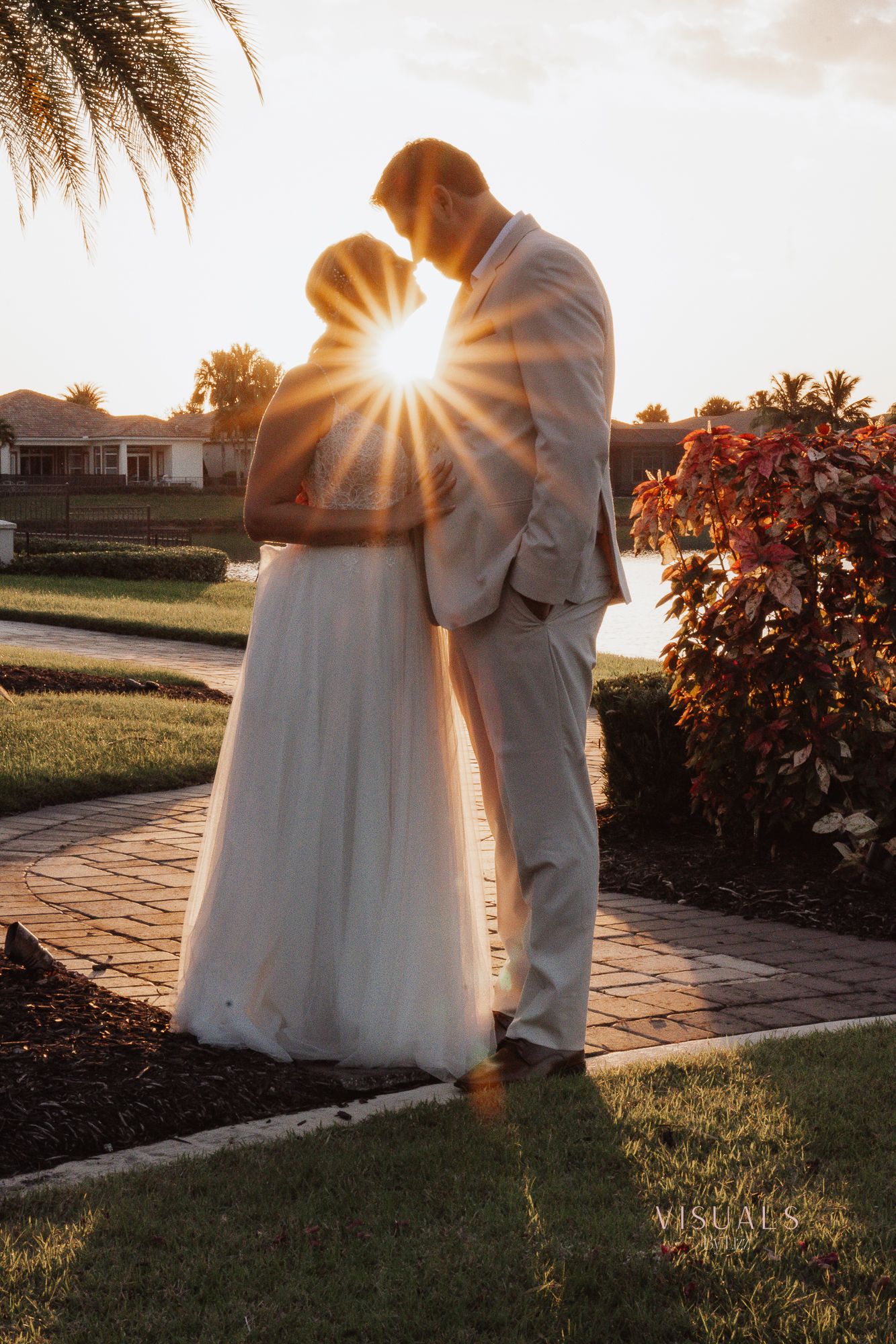 A romantic sunset wedding photo shoot on a stone path surrounded by lush gardens and warm golden light.