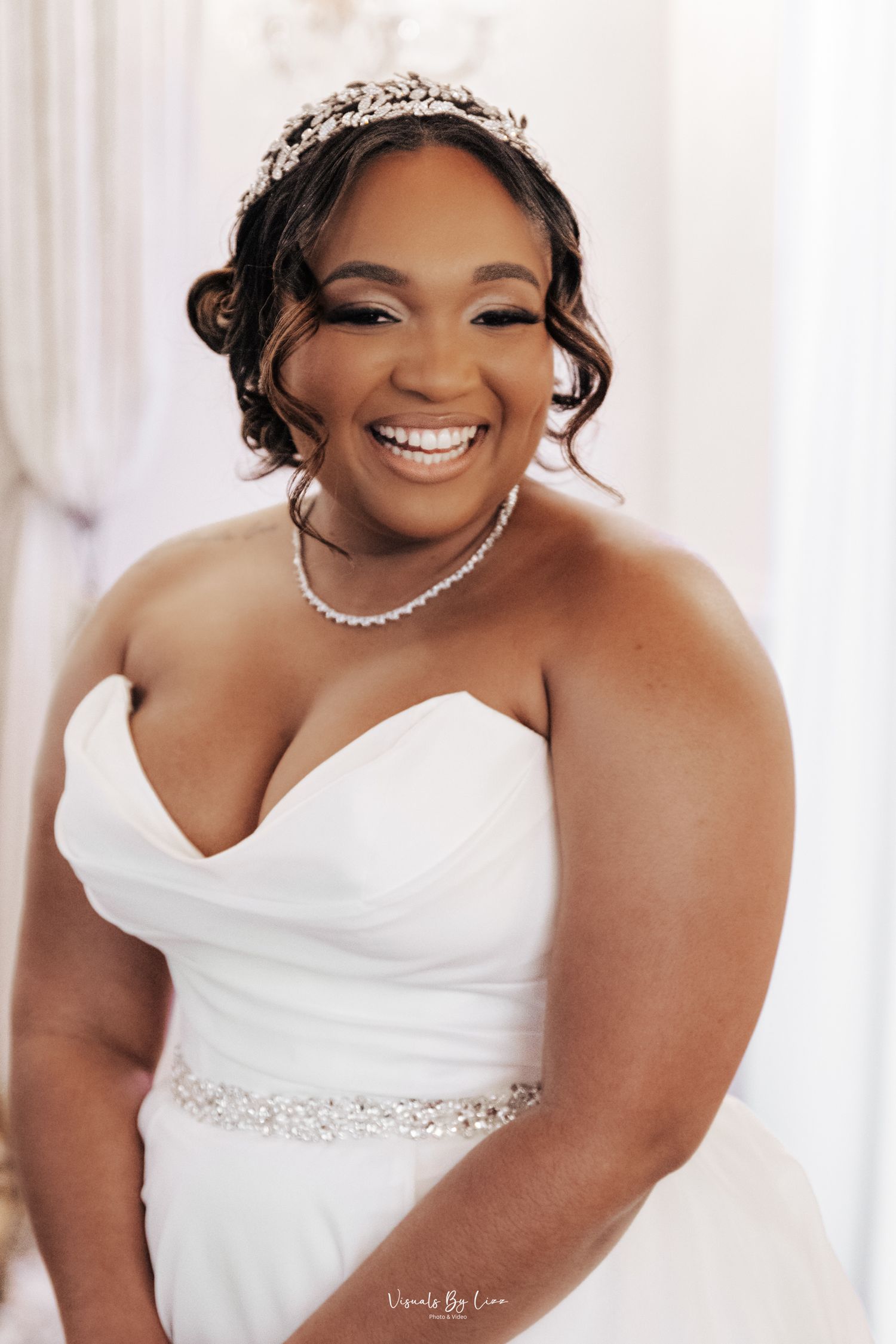 Beautiful bride in white strapless wedding dress smiling and wearing pearl jewelry in bridal portrait series.