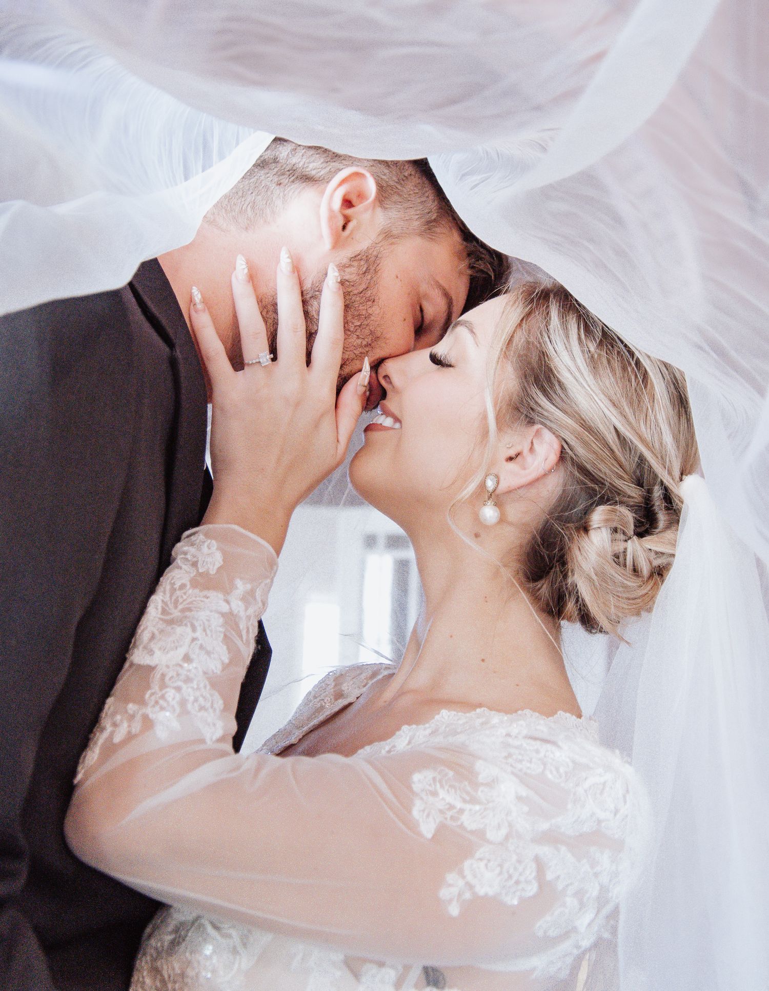 Intimate moment shared under flowing veil during romantic wedding photoshoot.